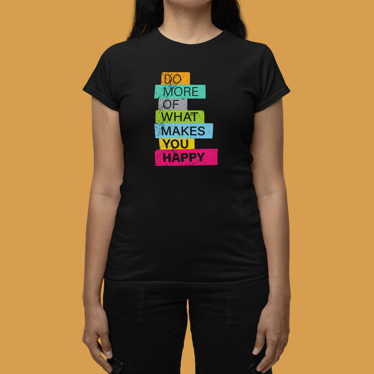 'Do More of What Makes You Happy' Women's T-Shirt in black, woman modeling against an orange backdrop