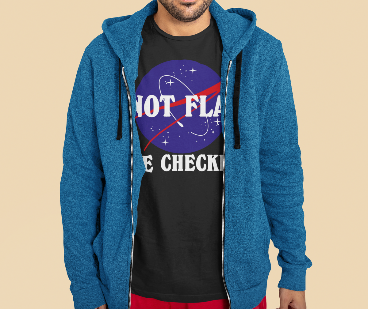 'Not Flat, We Checked' earth logo tee in black, man wearing it under a blue zip hoodie, funny science gift