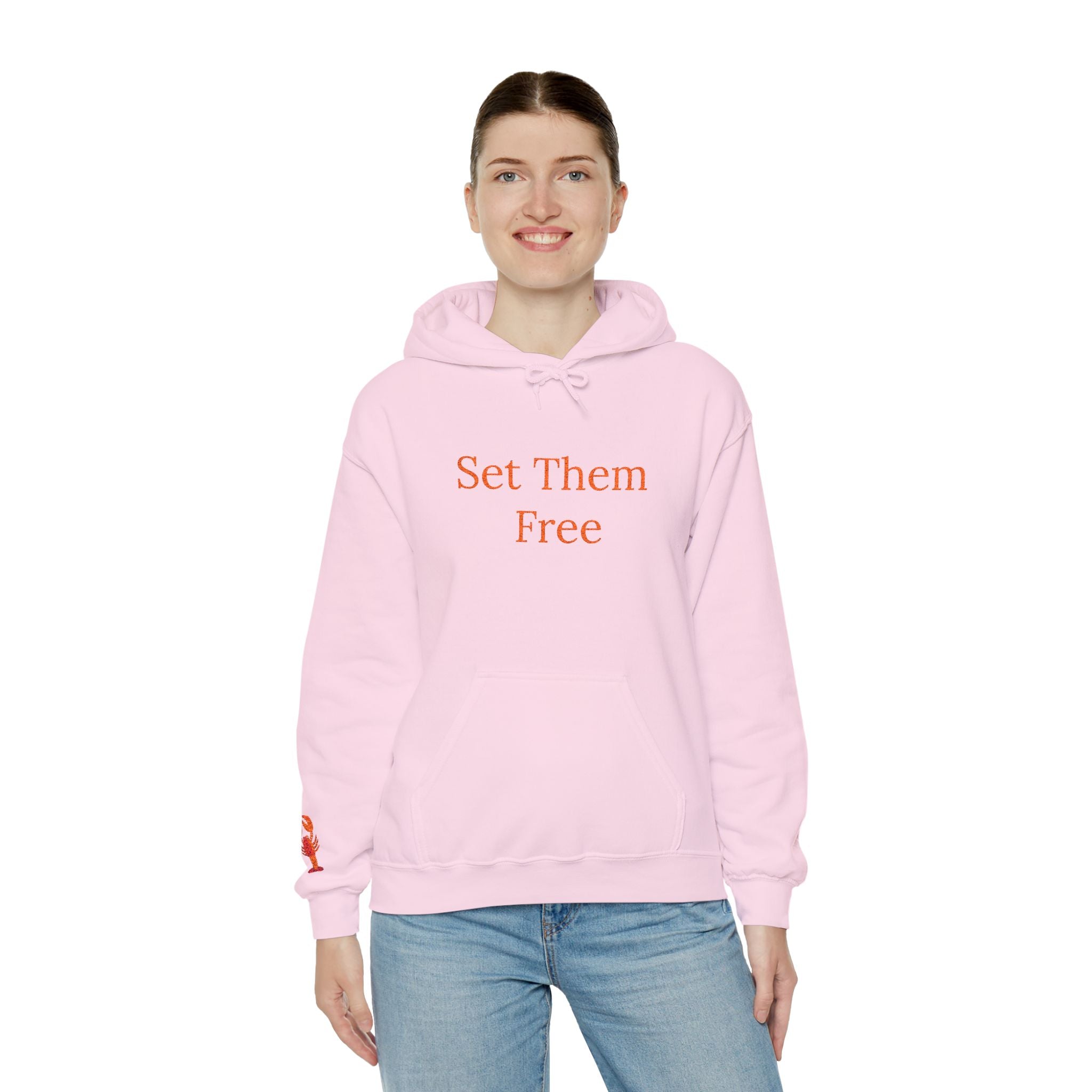A woman stands facing forward, wearing the Set Them Free Hoodie — Claude / OpenClaw Moltbot AI Graphic Hoodie in light pink, featuring "Set Them Free" printed in red on the front.