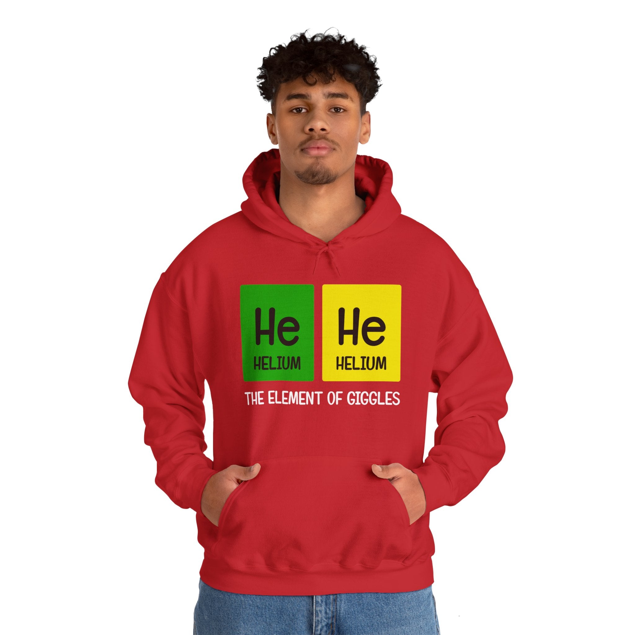 A person wearing a stylish **He-He - Hooded Sweatshirt** with "He Helium The Element of Giggles" printed on it, featuring two periodic table elements "He" in green and yellow squares. The design offers both comfort and a touch of whimsy.
