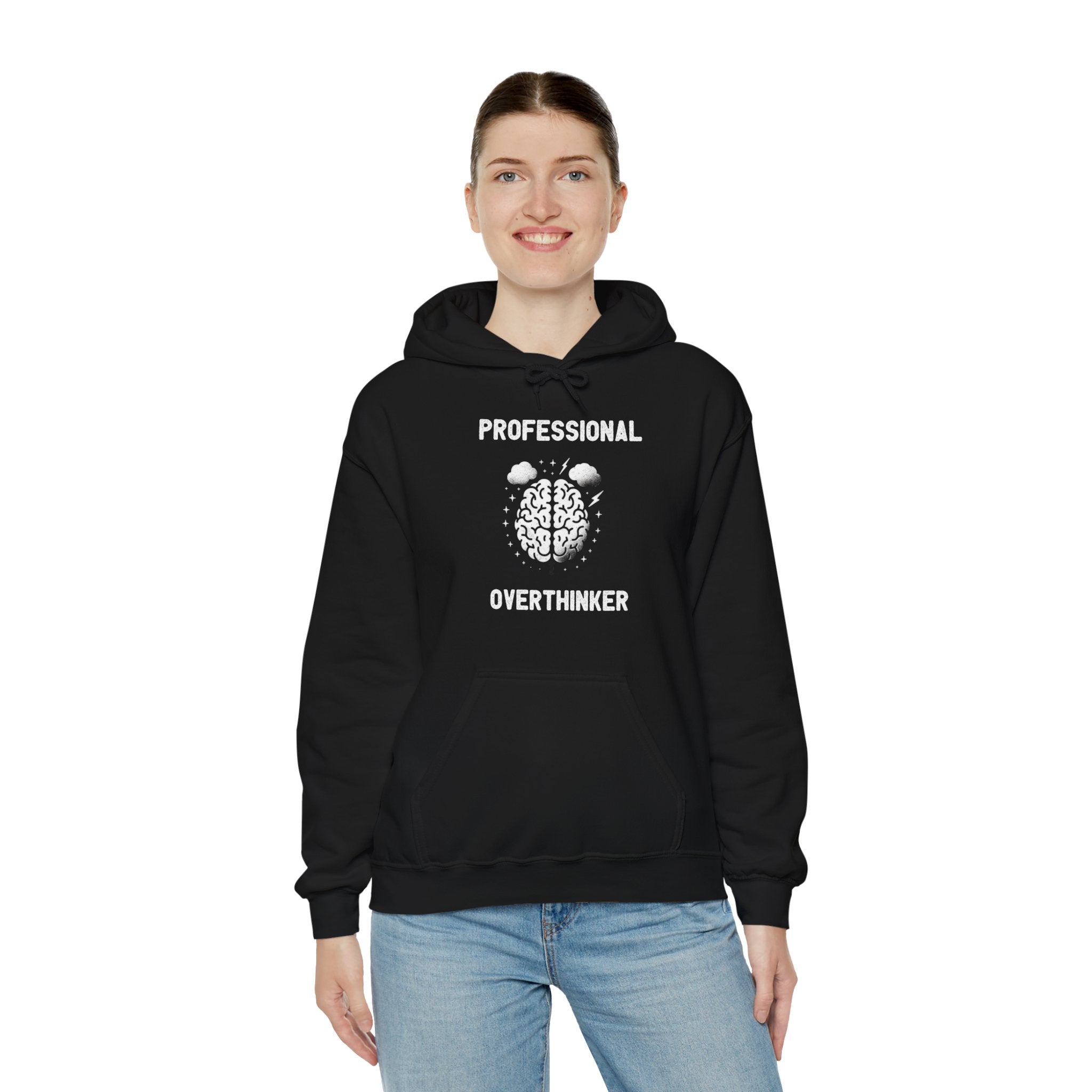 A person wearing a black **Professional Overthinker - Hooded Sweatshirt** that reads "Professional Overthinker" above and below a brain graphic, smiling and standing against a white background. The casual fashion effortlessly captures the thoughtful vibe.