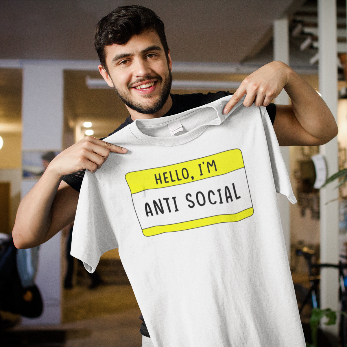 Hello I'm Anti Social name tag T-shirt in white, man holding it up indoors, funny sarcastic gift tee