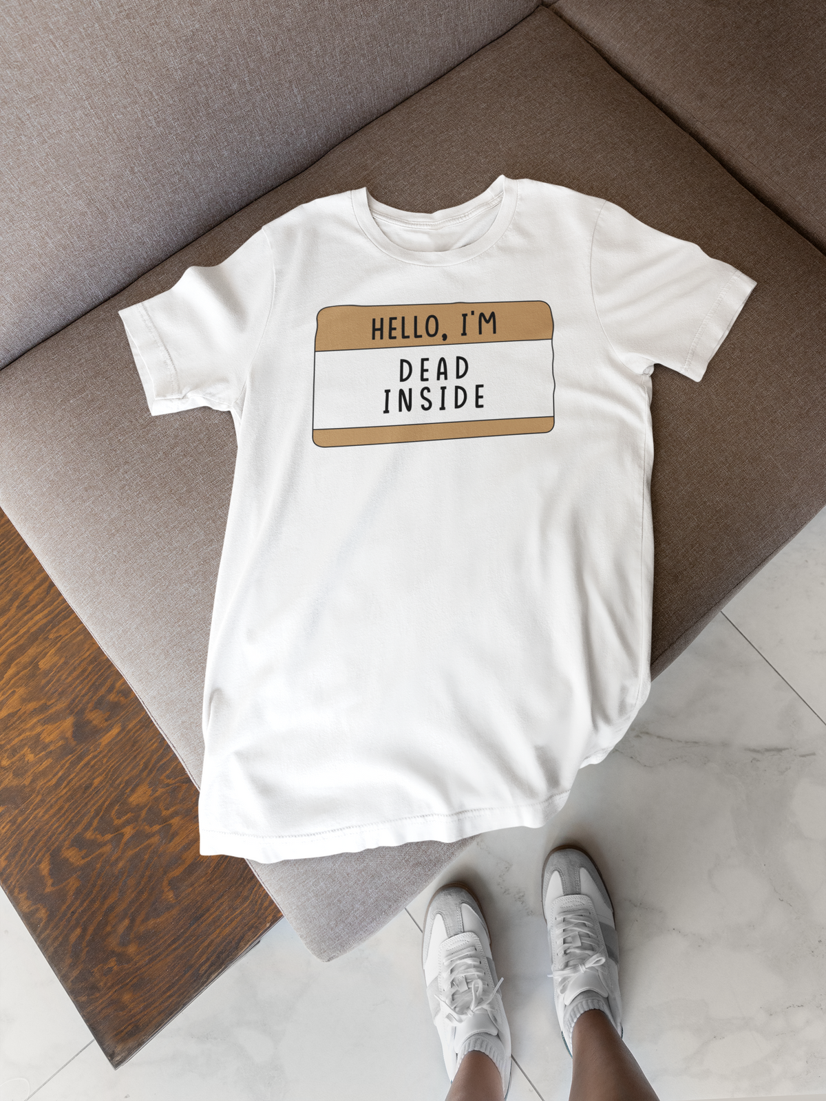 Hello I'm Dead Inside name tag T-shirt in white, flat lay on wood floor with shoes, funny gift tee