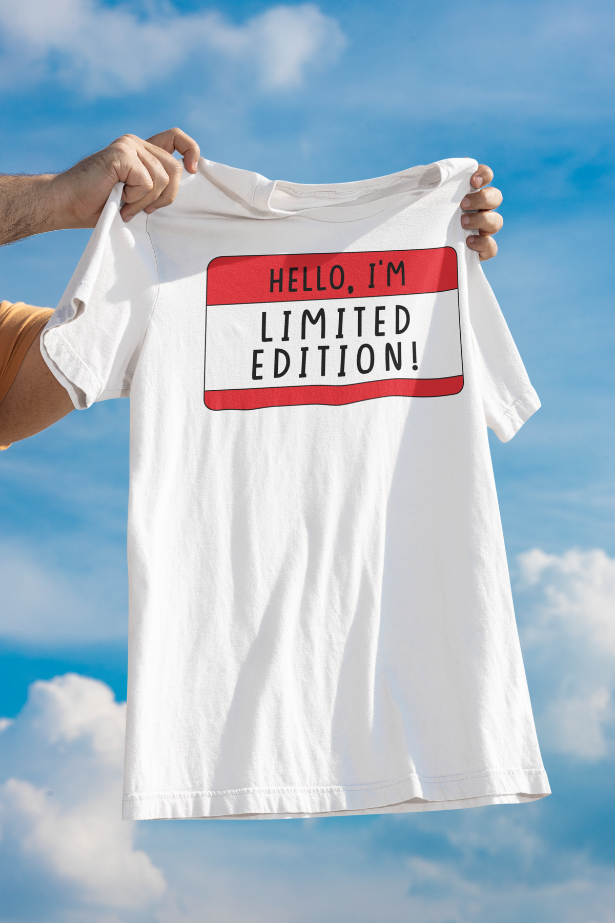 Hello I'm Limited Edition name tag T-shirt in white, man holding it up against sky backdrop, gift tee