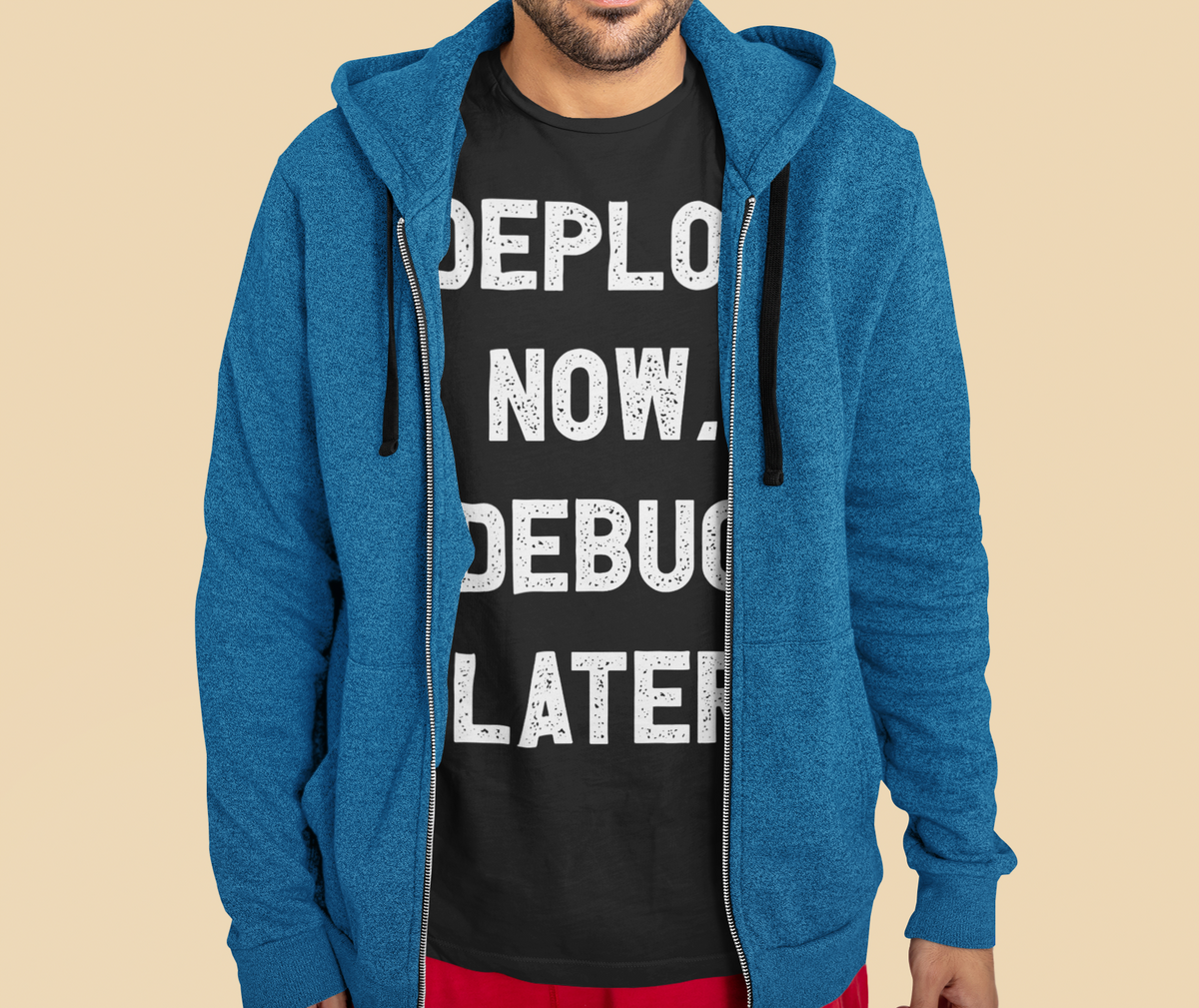 'Deploy Now, Debug Later' t-shirt in black, man wearing it under open hoodie, funny gift for programmers