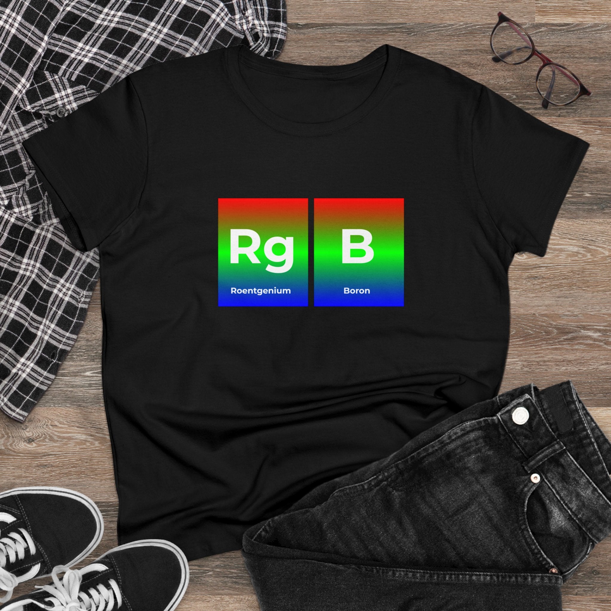 RG-B - Women's Tee on wooden floor with RGB-themed periodic table elements "Rg" for Roentgenium and "B" for Boron. Surrounded by black-and-white checkered fabric, black jeans, glasses, and black sneakers, this cotton RG-B piece epitomizes ethical fashion.