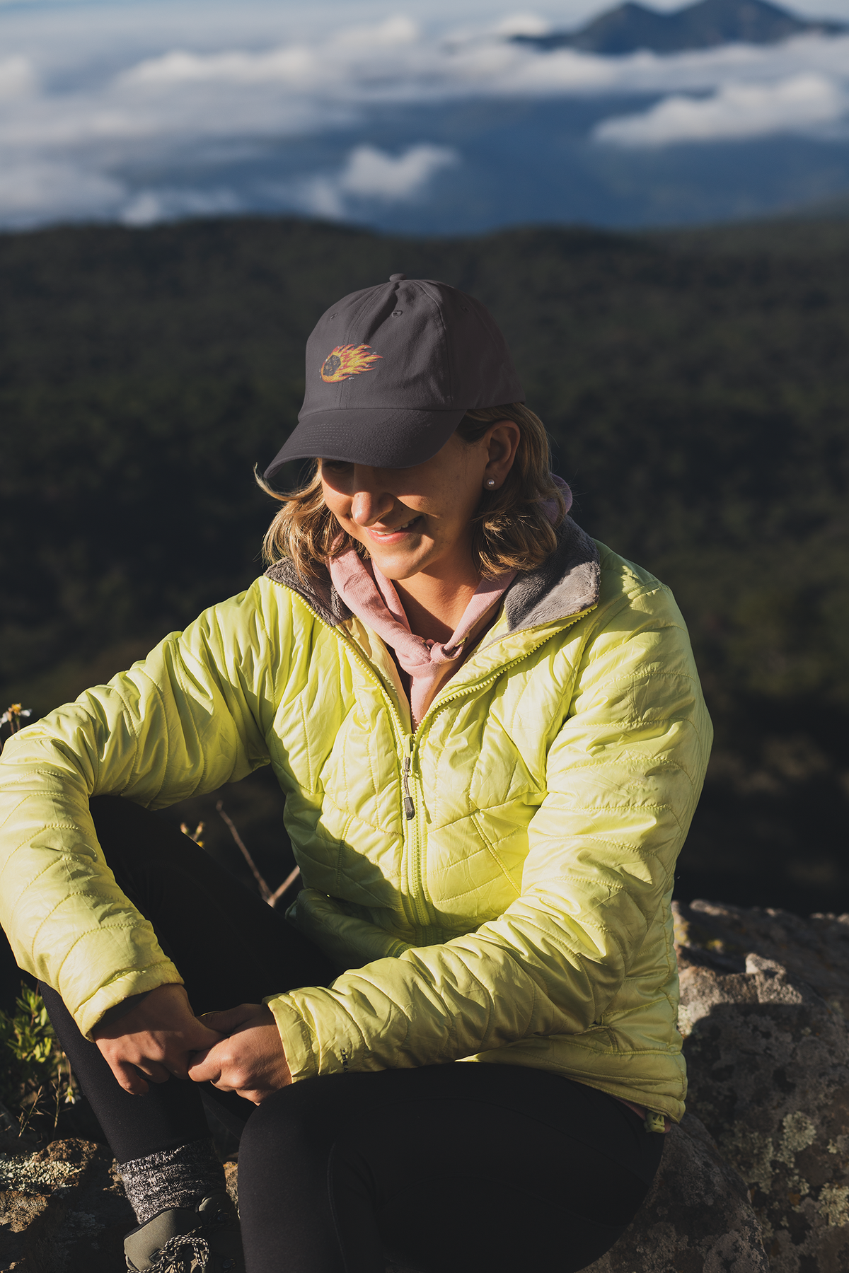 Polyhedral Dice On Fire embroidered D&D dad hat, woman on a mountain hike, lifestyle mockup, Geekpsters