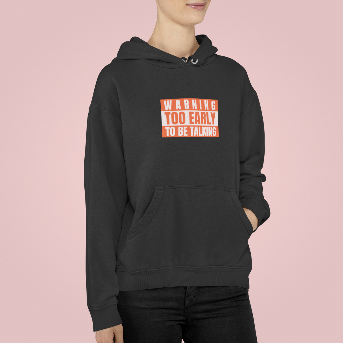 'Warning Too Early To Be Talking' morning hoodie in black, woman wearing it, pink background, funny gift
