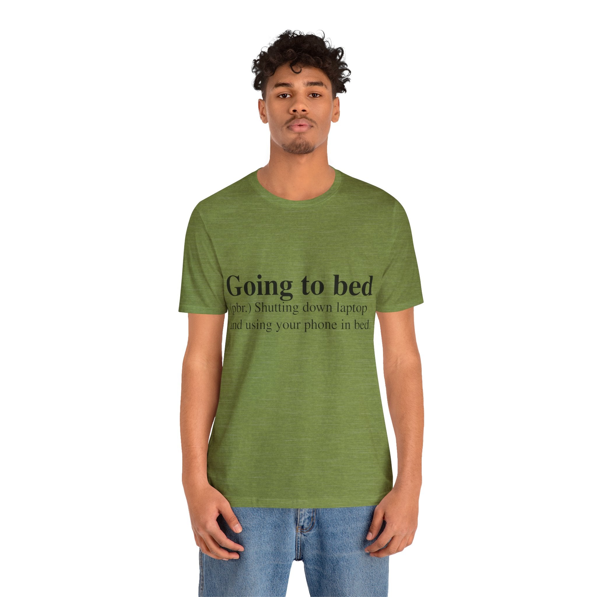 A young man wearing a Going to Bed T-Shirt with the text "going to bed? shutting down laptop and using your phone in bed" printed on it.