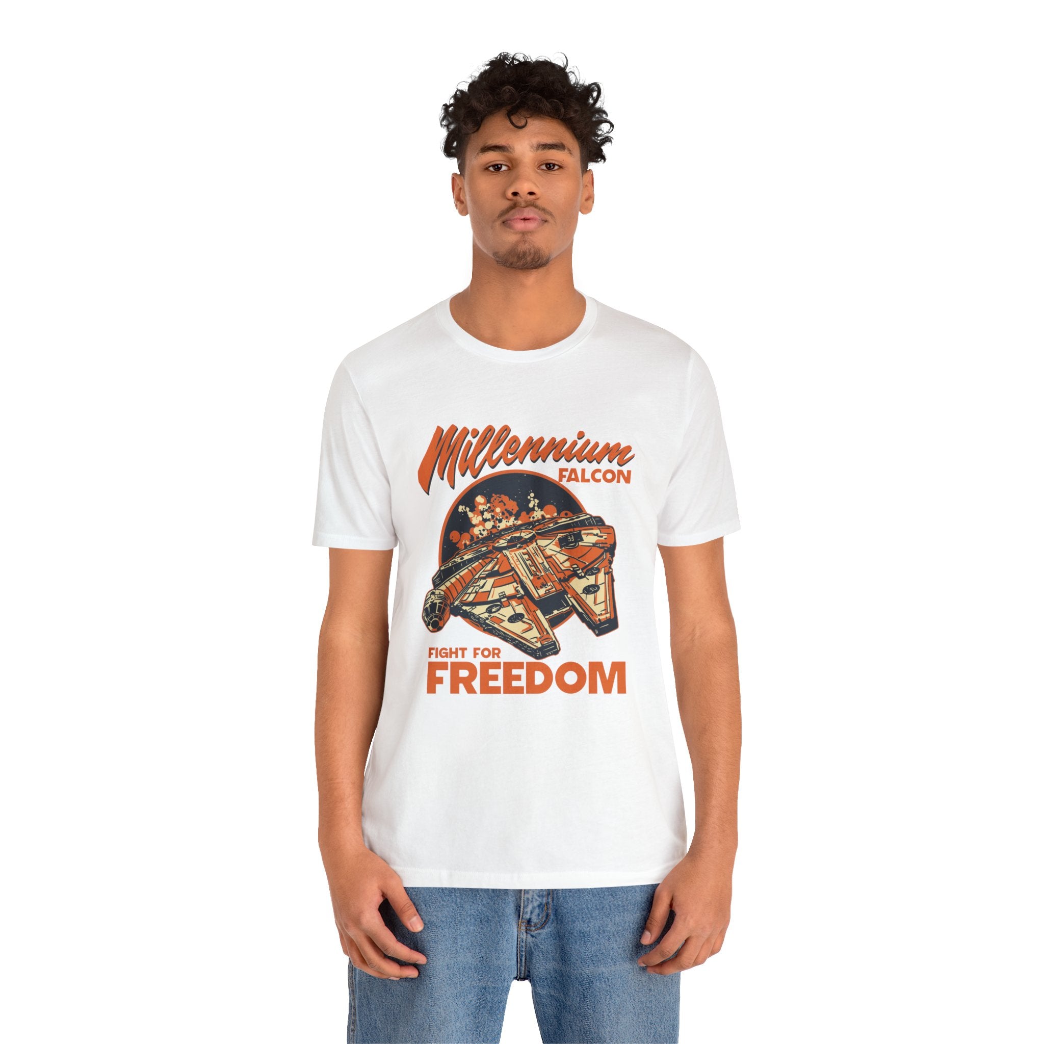 A young man wearing a white unisex jersey tee with a quality Falcon print and the phrase "fight for freedom," paired with blue jeans.