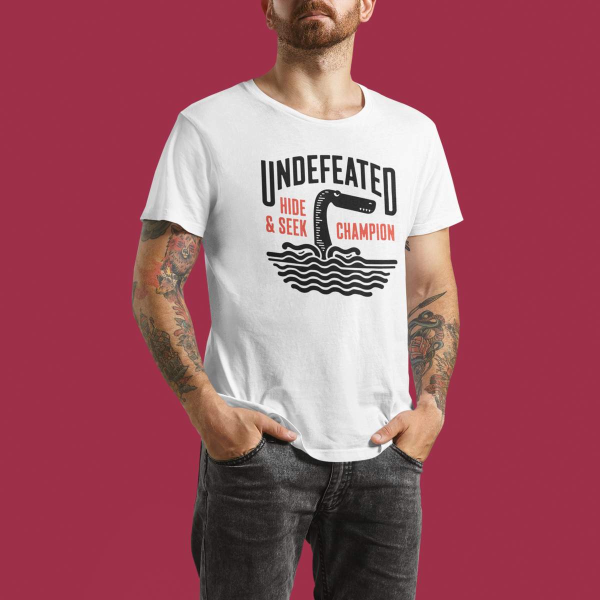 "Undefeated Hide and Seek Champion" t-shirt in white, man modeling it in a studio, funny game gift