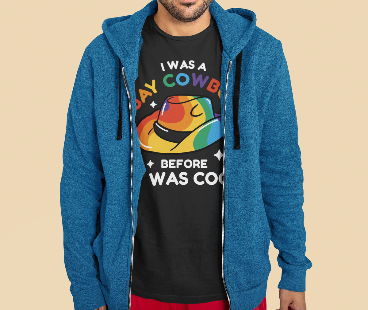 'I Was a Gay Cowboy Before It Was Cool' T-shirt, man wearing it under a blue hoodie, funny pride gift