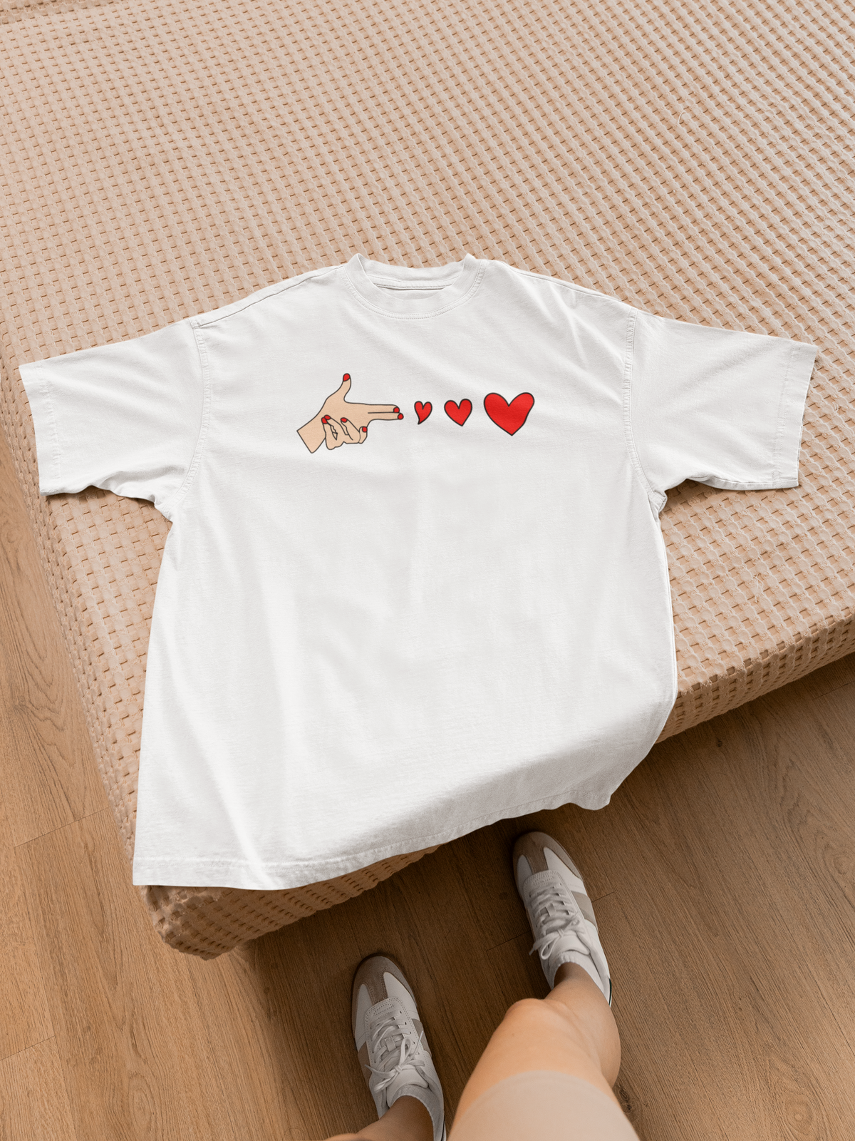 Bang Bang finger gun heart tee in white, flat lay on a bed with sneakers, funny sarcastic gift shirt