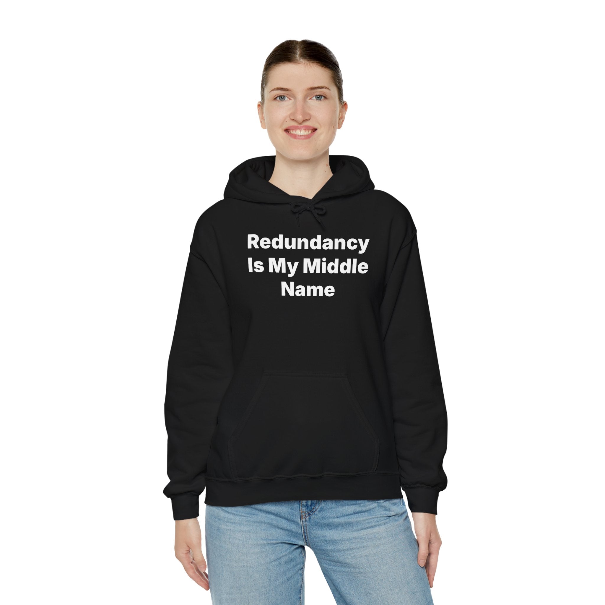 A person stands against a plain background, smiling warmly while wearing the "Redundancy Is My Middle Name" hooded sweatshirt in cozy black.