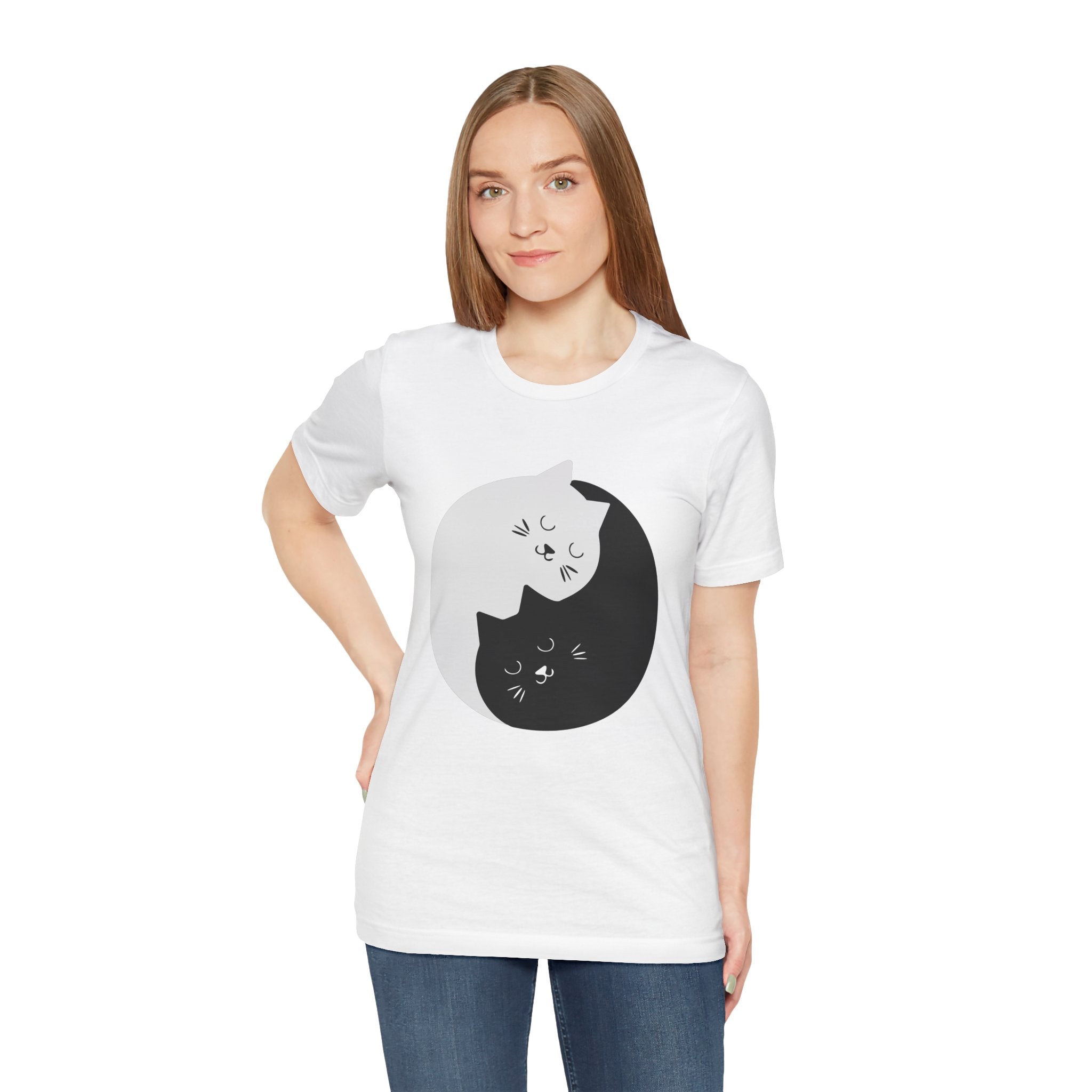 Young woman wearing a soft cotton, white unisex tee with a graphic of two cats, one black and one white, in a YING-ANG KITTIES T-Shirt design.
