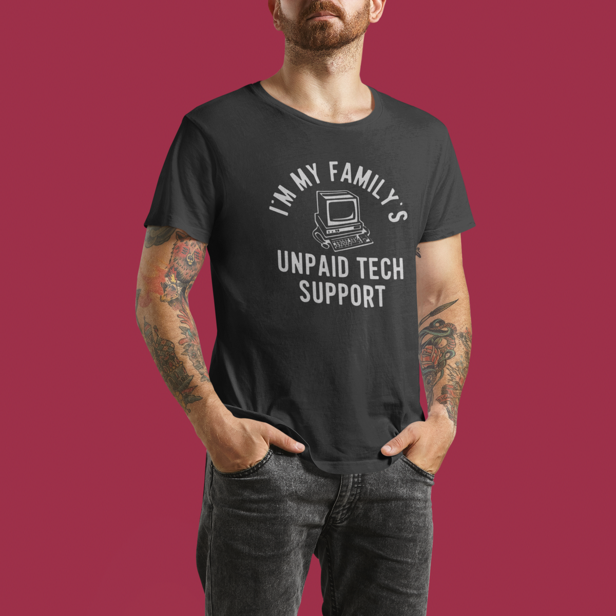 I'm My Family's Unpaid Tech Support charcoal t-shirt worn by a tattooed man, maroon background, funny IT gift