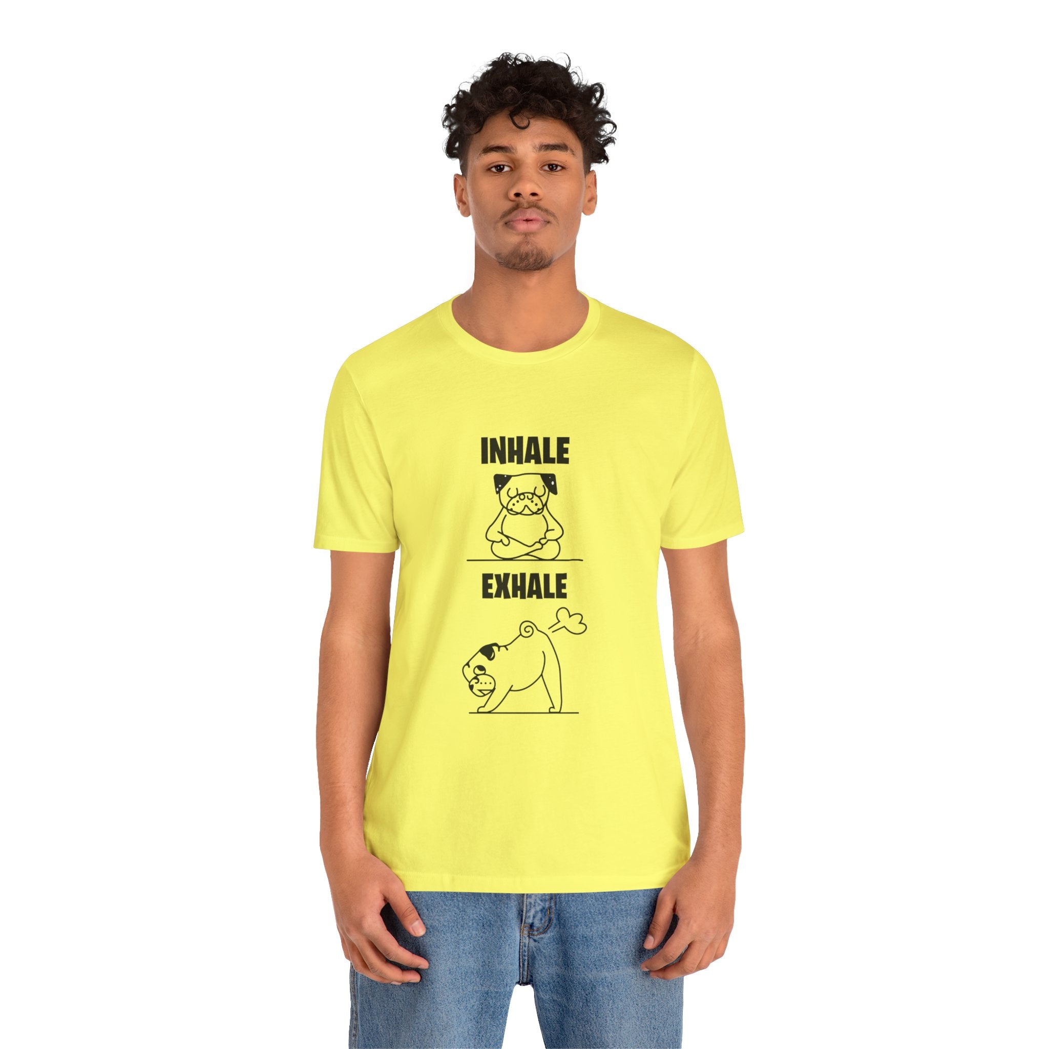 A young man wearing a yellow unisex Dog Funny T shirt featuring a meditating dog and a cat print, paired with blue jeans, standing against a white background.