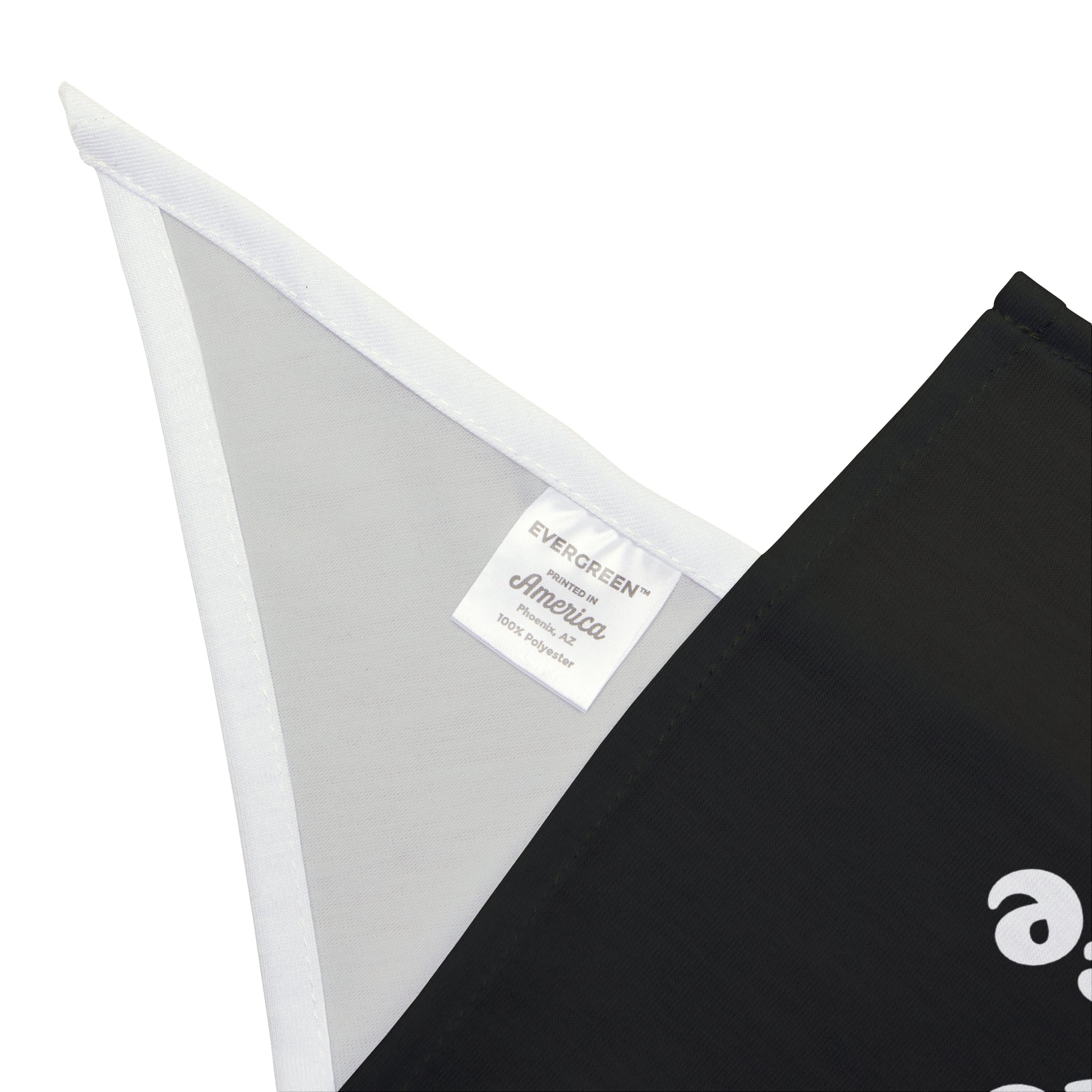 Close-up of a black fabric banner with a white triangular section displaying a tag that reads "EVERGREEN America, 100% Poly." This stylish piece, known as the Load Balanced Life - Pet Bandana, is crafted from soft-spun polyester, ensuring both durability and elegance.