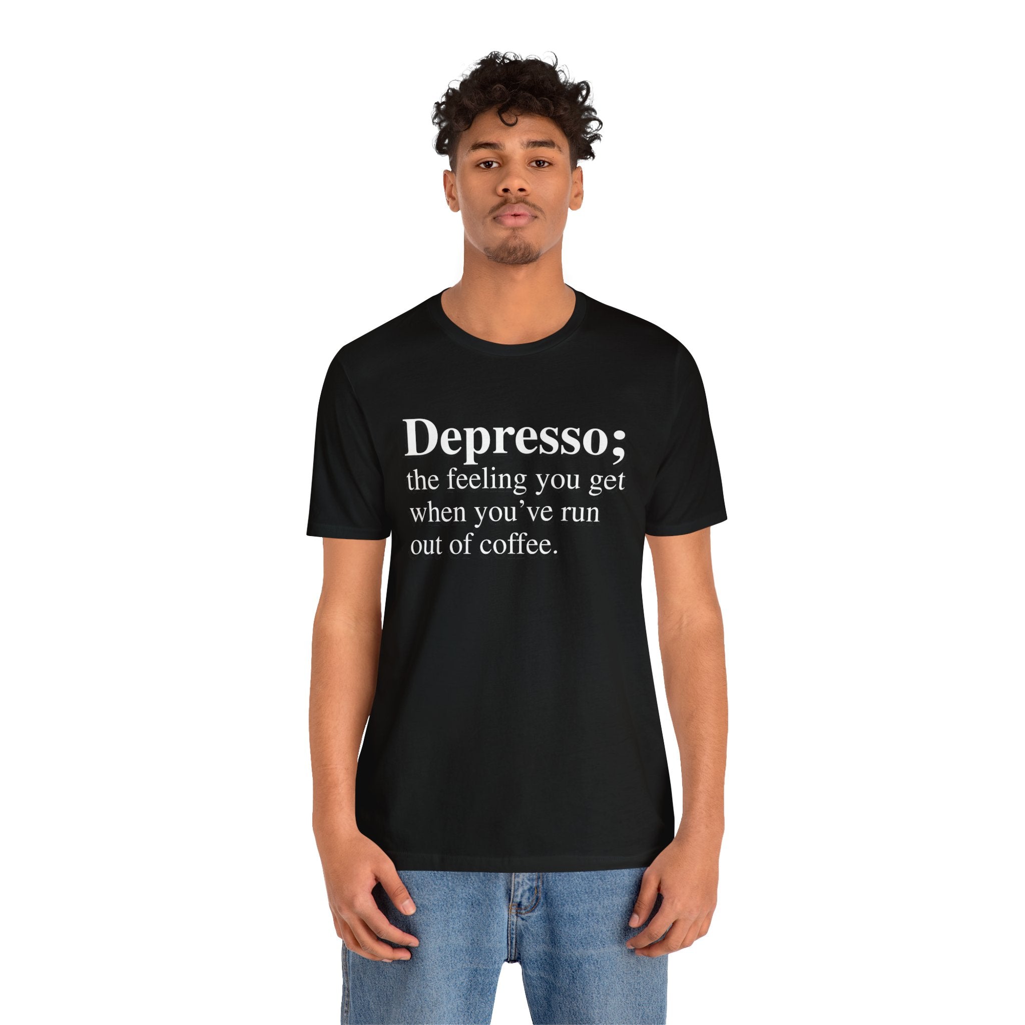A young man is wearing a soft cotton, black Depresso T-Shirt with the text "Depresso; the feeling you get when you've run out of coffee," and he stands facing the