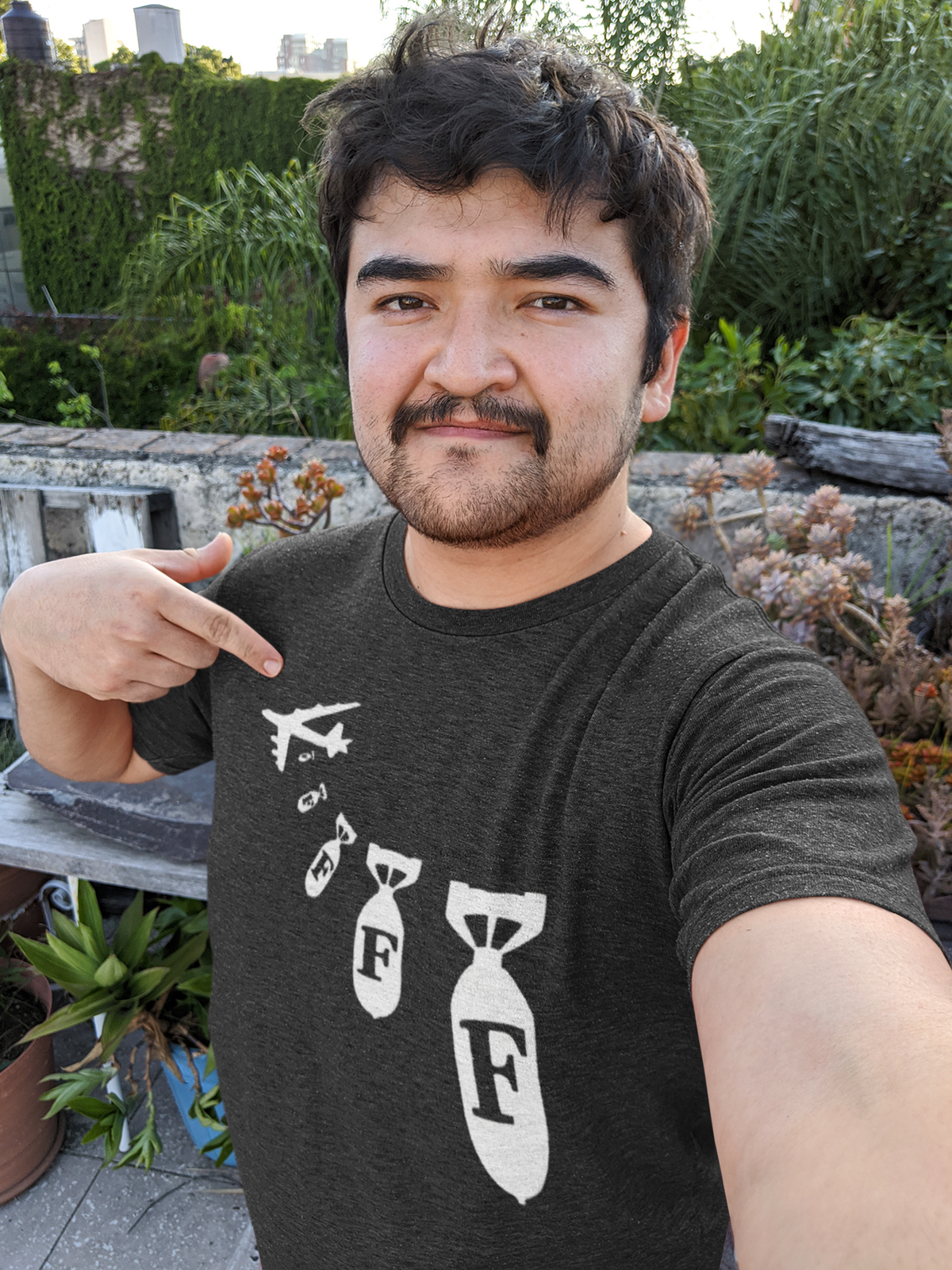 "F Bomb" t-shirt in charcoal, man pointing outdoors in a garden, funny sarcastic gift t-shirt