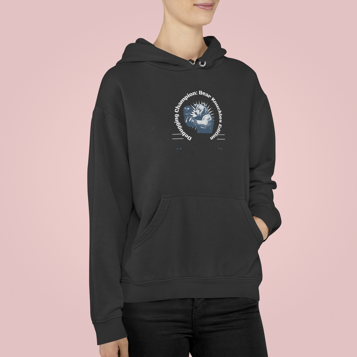 'Debugging Champion' bear graphic hoodie in charcoal, woman wearing it, pink backdrop, coder gift