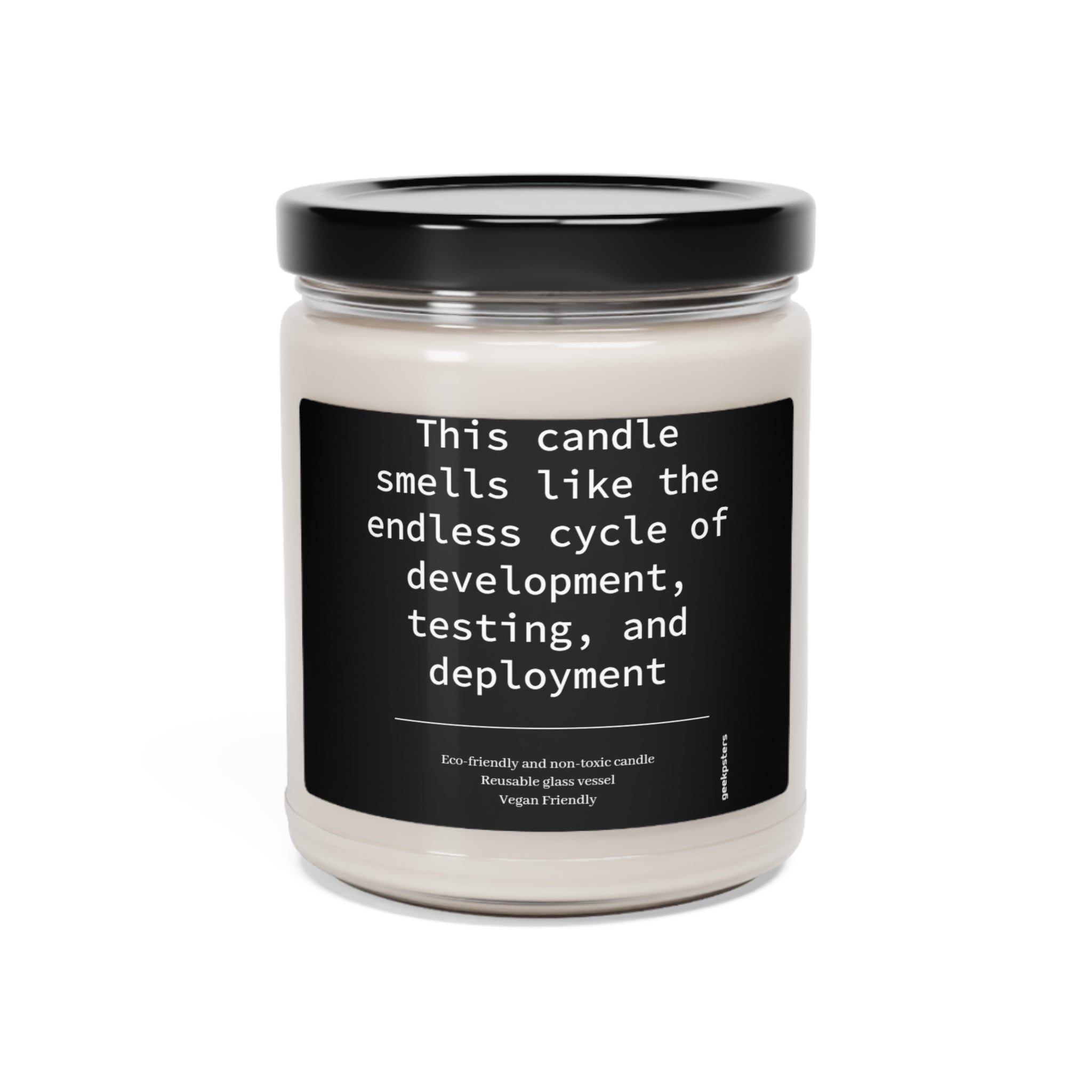 A scented soy candle in a clear jar with a label that reads "this candle smells like the endless cycle of software development, testing, and deployment." Eco-friendly and vegan-friendly details are also noted.