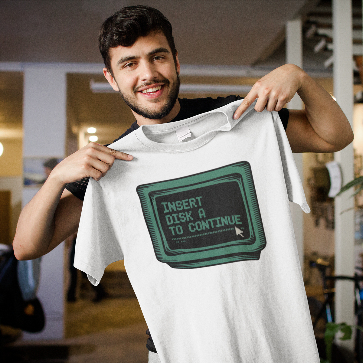 'Insert Disk A To Continue' oversized tee in white, man holding it up indoors, funny gift for programmers