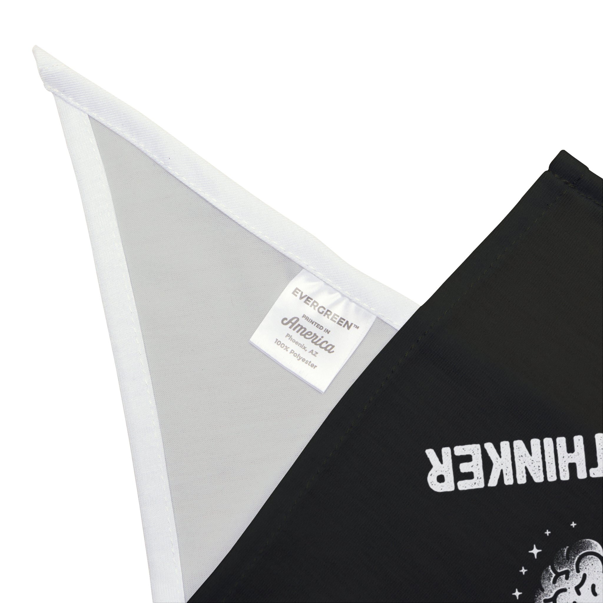 A close-up image showing the white tag on a black fabric with printed text. The tag reads "EVERGREEN, America" and "100% soft-spun polyester." The fabric, part of the Professional Overthinker - Pet Bandana collection, also has partially visible white text.