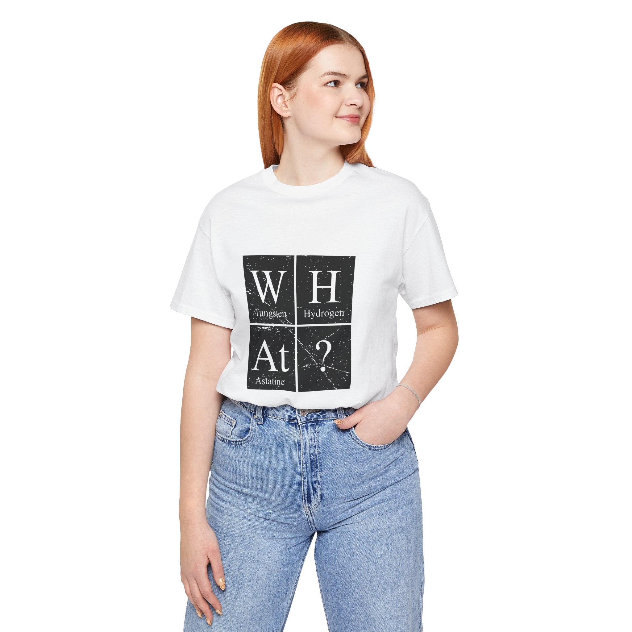 Woman in white W-H-At-? jersey tee with periodic table design and blue jeans, standing with hands in pockets, looking to the side.