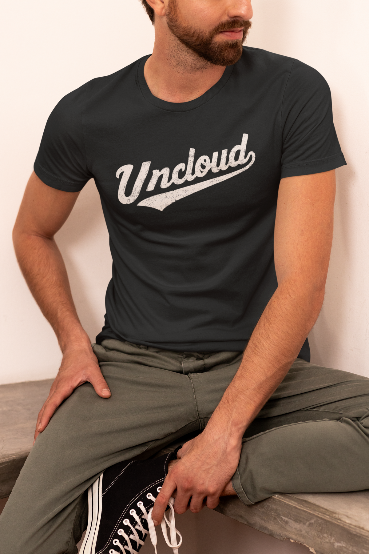 'Uncloud' script logo t-shirt in black, man kneeling wearing it, funny gift for developers