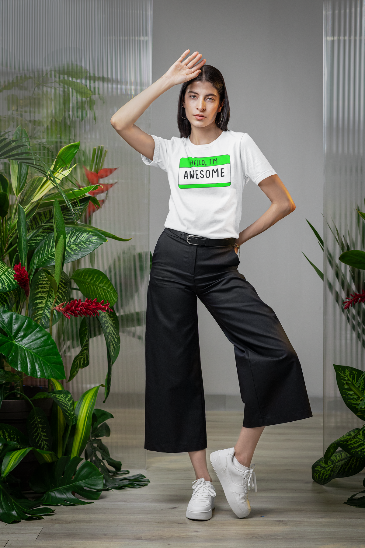 Hello I'm Awesome name tag T-shirt in white, woman posing among plants, funny confidence gift tee