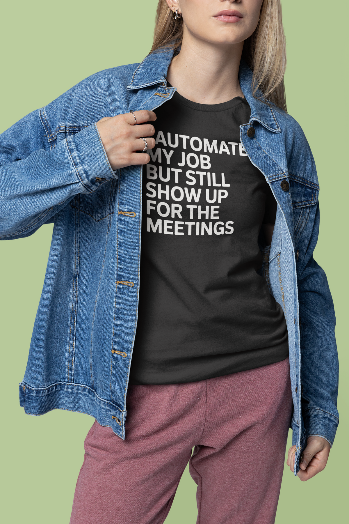 'I Automated My Job But Still Show Up for the Meetings' t-shirt in black, woman wearing it under denim jacket, developer gift