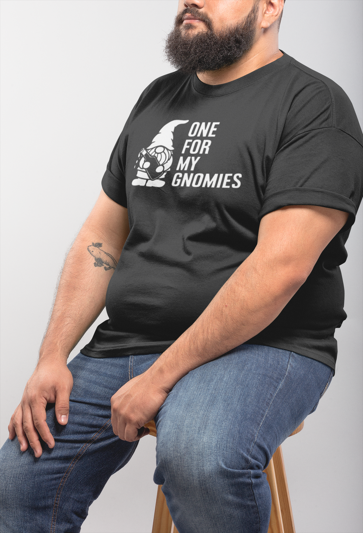 One For My Gnomies t-shirt in black, heavyset man wearing it seated indoors, funny gift for him