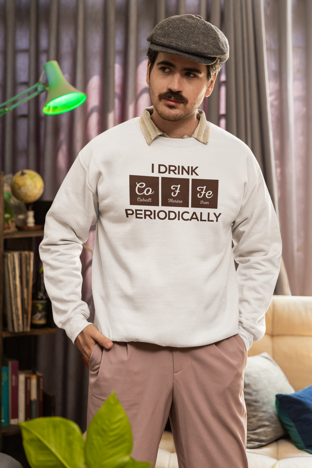 'I Drink Coffee Periodically' sweatshirt in tan, man wearing it indoors with newsboy cap, funny caffeine lover gift