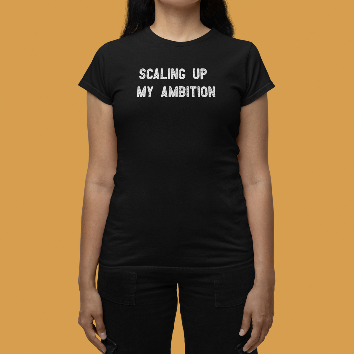 'Scaling Up My Ambition' women's t-shirt in black, woman wearing it on orange background, funny motivational gift