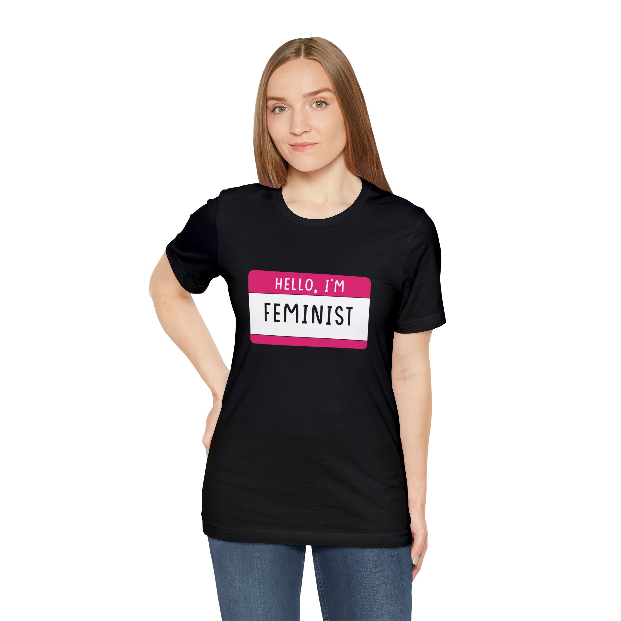 Young woman wearing a black Hello, I'm Feminist t-shirt with a pink name tag design that reads "hello, i'm feminist.
