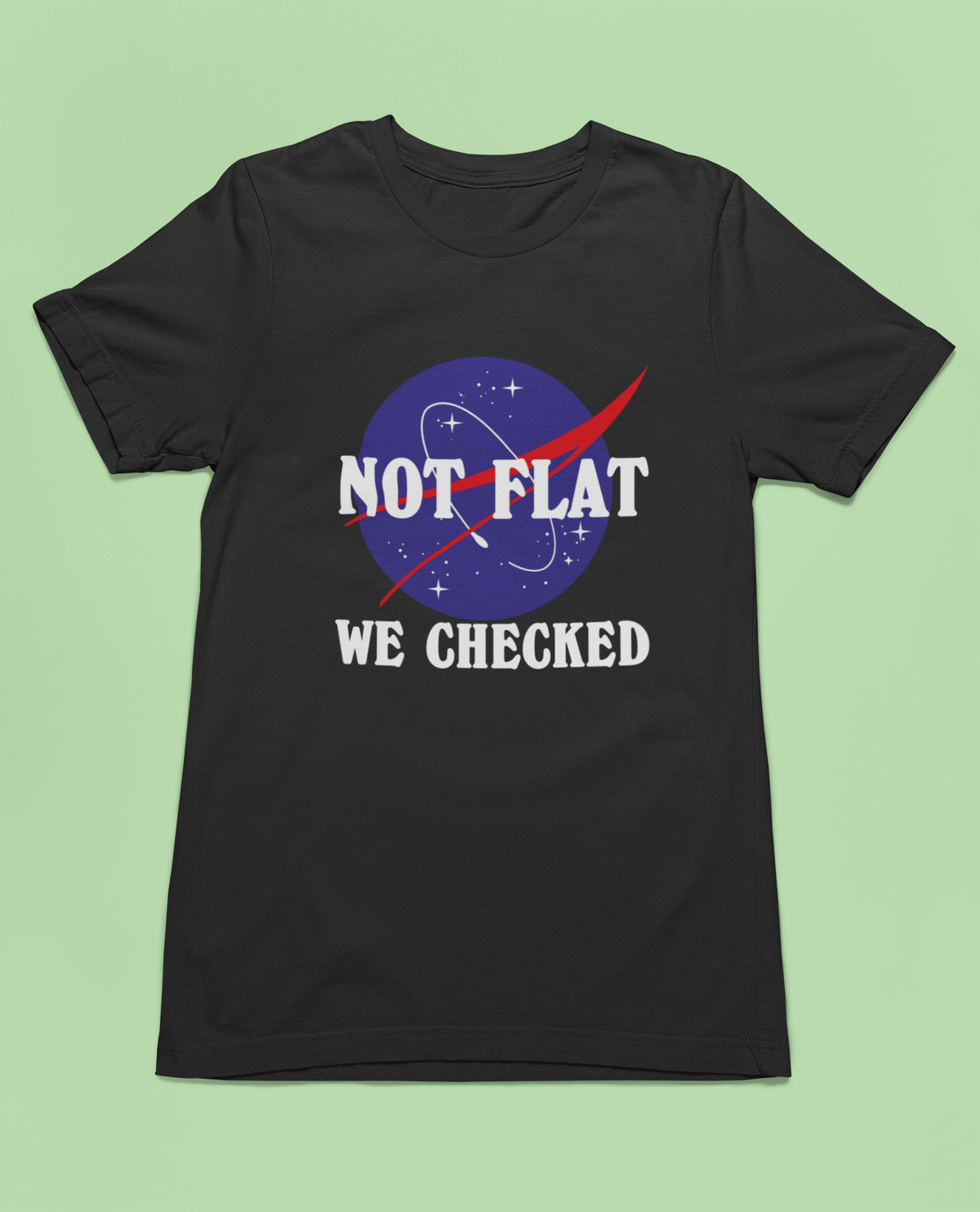 'Not Flat, We Checked' earth logo t-shirt in black, flat lay on a green background, funny science gift