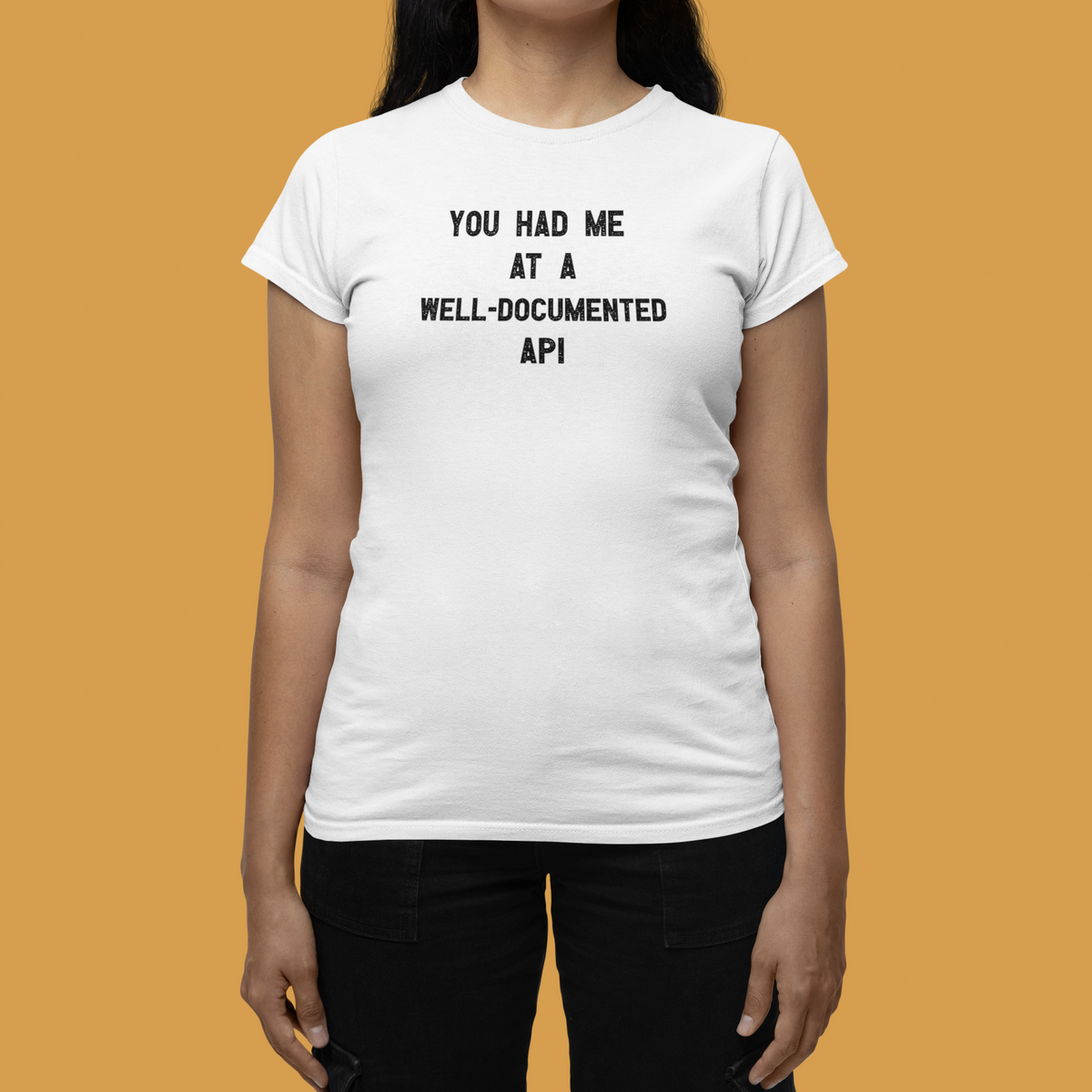'You Had Me at a Well-Documented API' women's tee in white, woman wearing it against a yellow backdrop, funny programmer gift