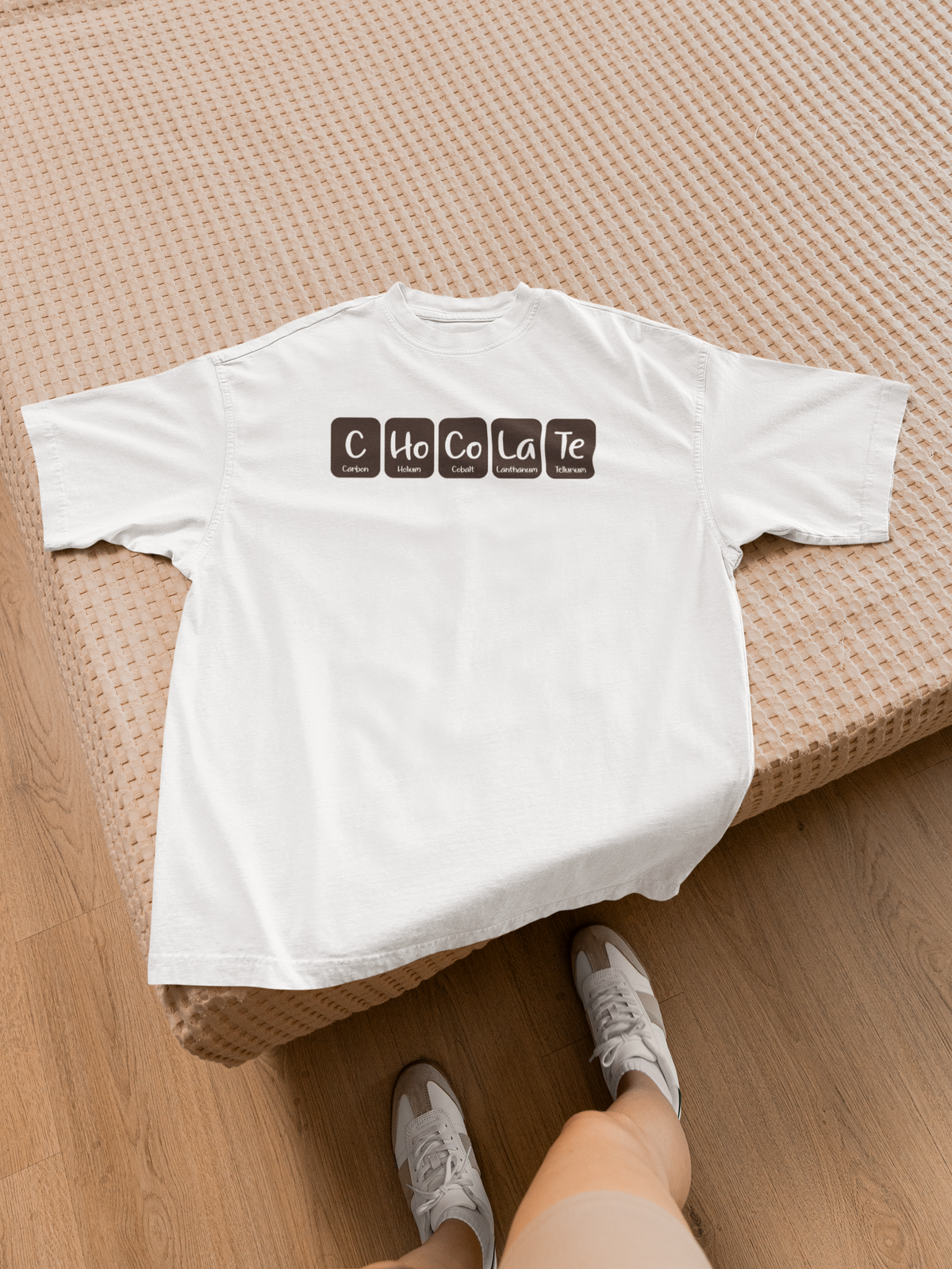 "Chocolate" periodic table t-shirt in white, flat lay on wooden surface, funny science pun shirt for foodies