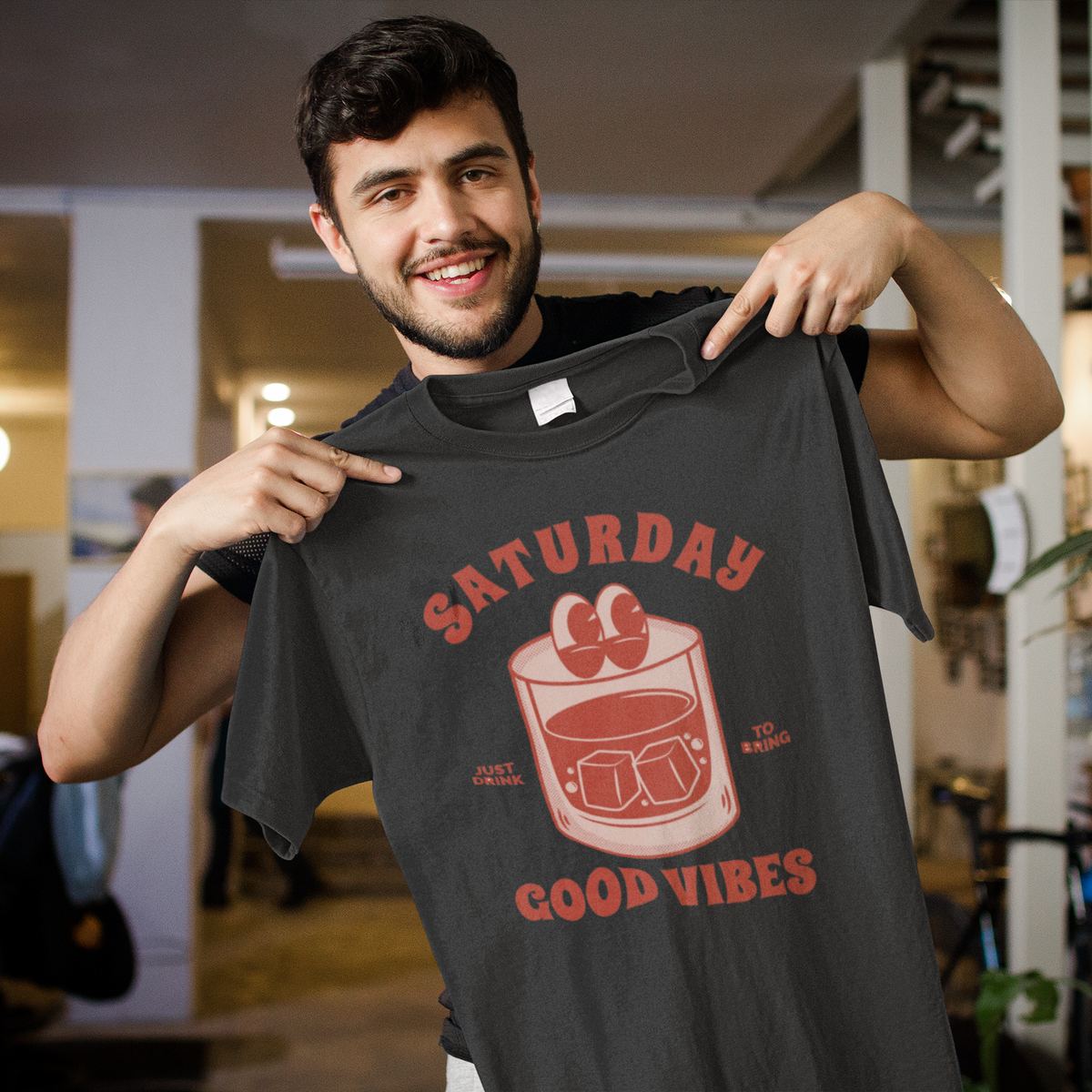 'Saturday Good Vibes' t-shirt in black, smiling man holding it up, funny weekend gift shirt