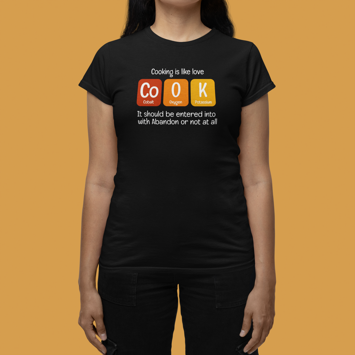 'Cook' t-shirt in black, woman wearing it against orange backdrop, funny kitchen pun gift