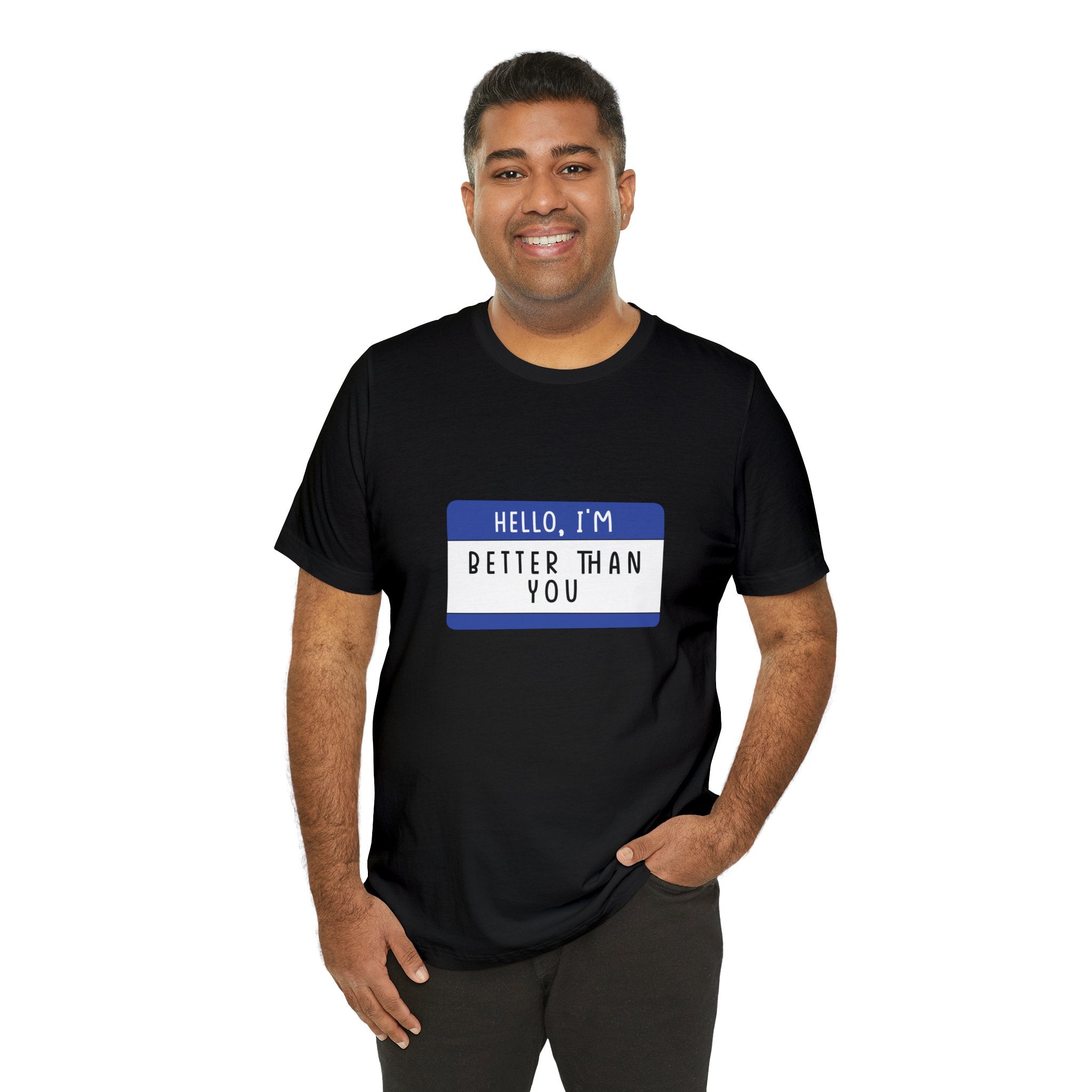 A man smiling and wearing a black "Hello, I'm Better Than You" t-shirt with geeky charm, featuring a blue name tag graphic.