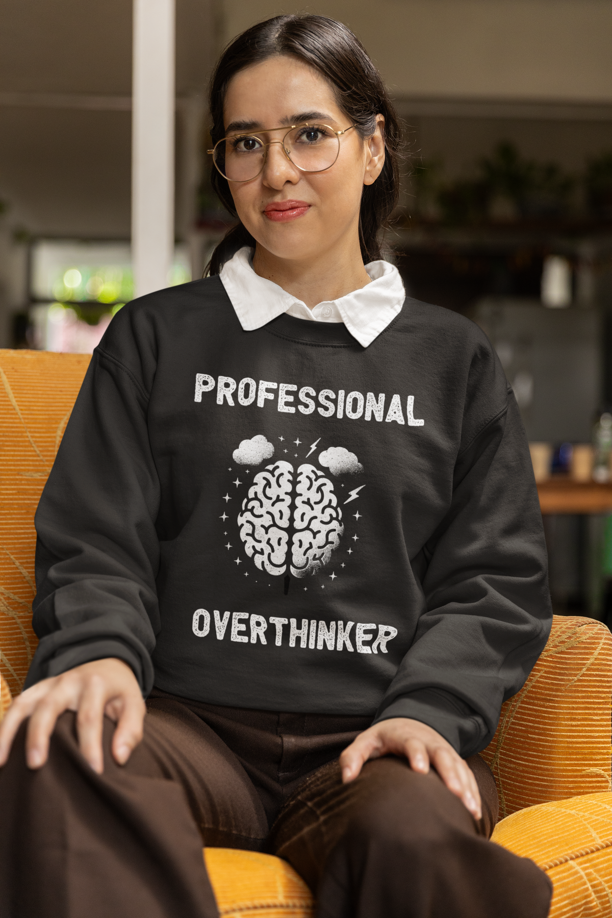 'Professional Overthinker' sweatshirt in black, woman sitting indoors, funny brain sweatshirt gift