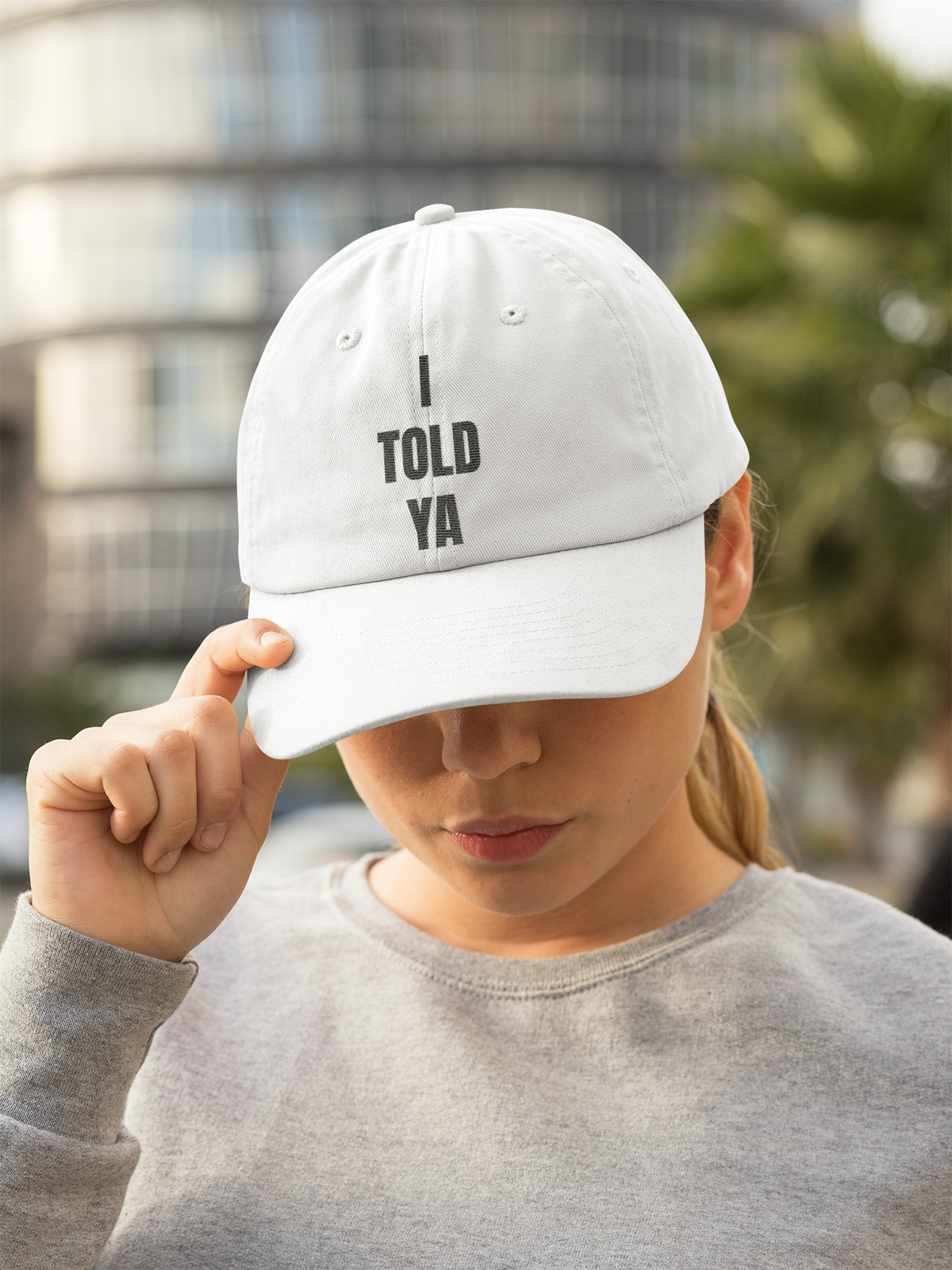"I Told Ya" slogan dad hat in white, woman wearing it outdoors in the city, funny quote cap gift