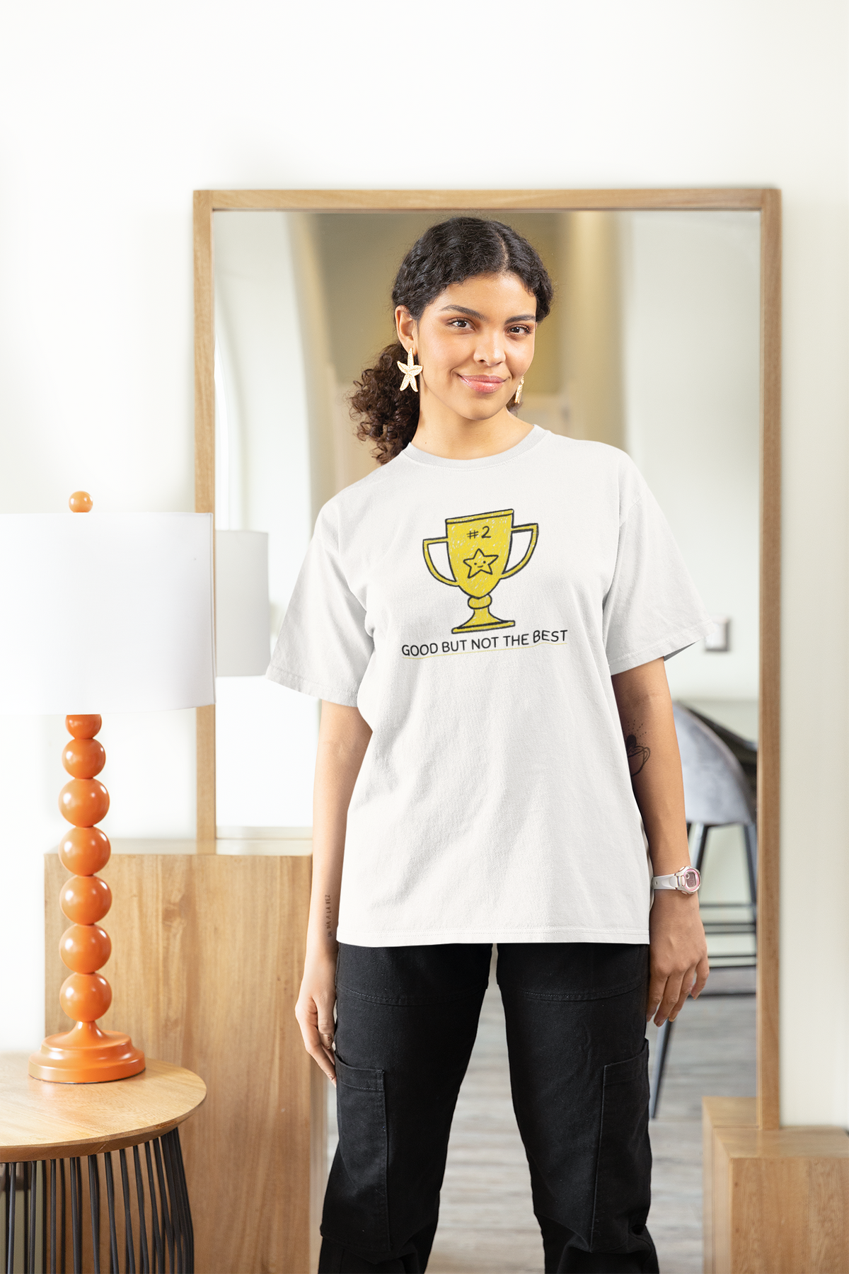 'Good But Not the Best' trophy tee in white, woman wearing it at home, funny graphic t-shirt for her