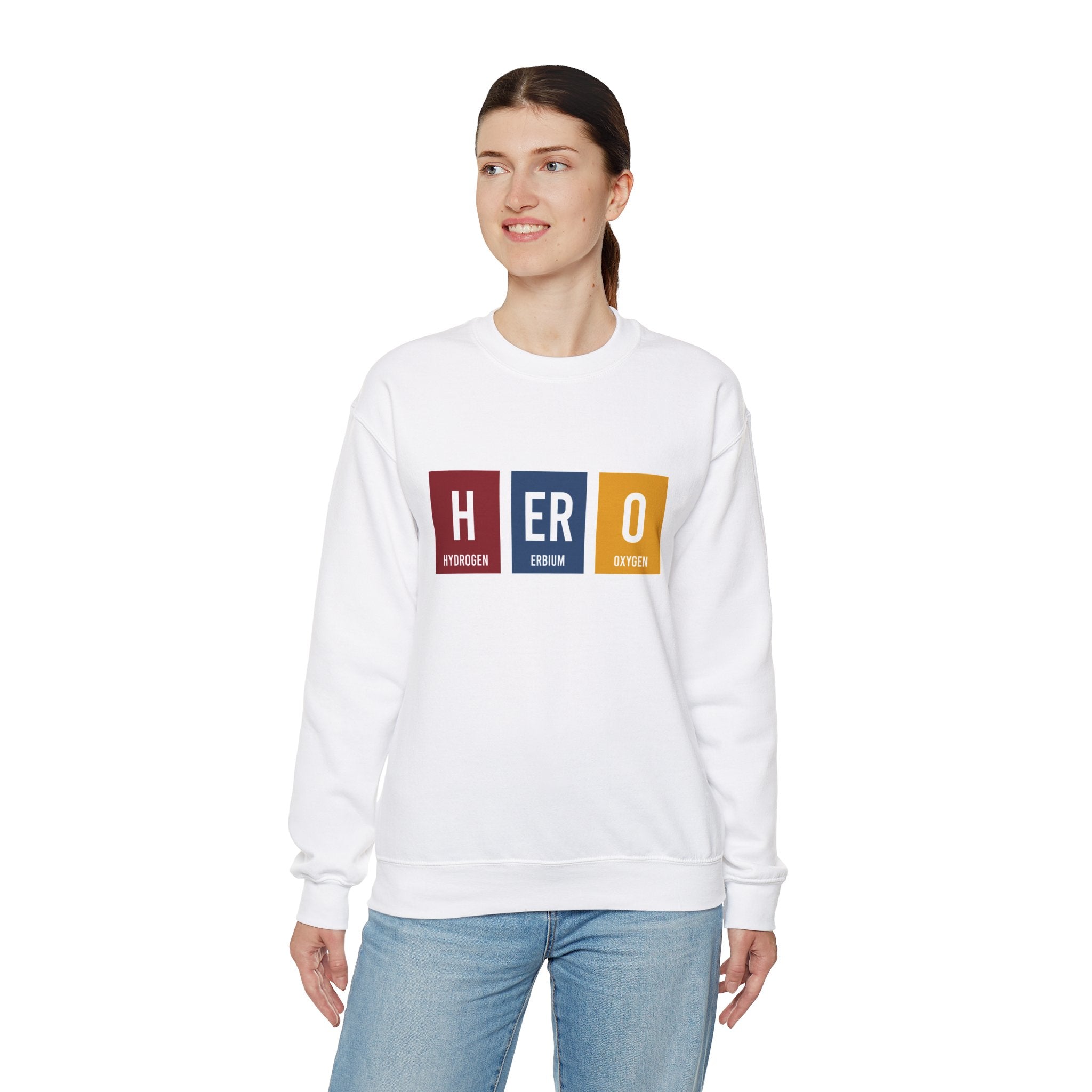 A person wearing a HERO - Sweatshirt designed sweatshirt featuring the text "HERO" spelled using periodic table elements: Hydrogen (H), Erbium (Er), and Oxygen (O). The comfortable sweatshirt blends warmth and style, perfect for making winters warmer. They have a neutral facial expression.