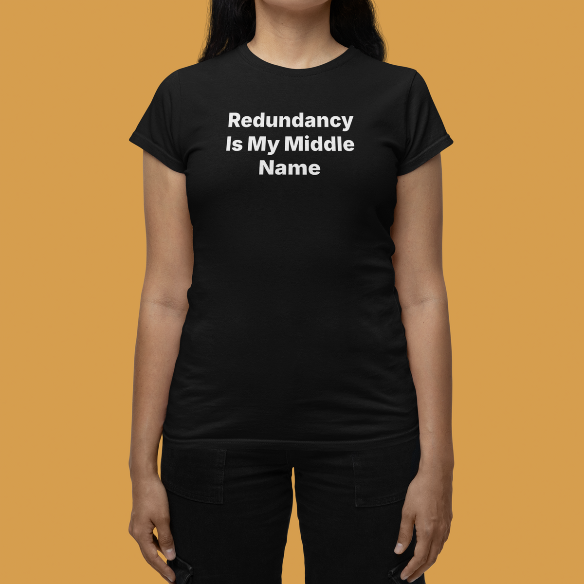 'Redundancy Is My Middle Name' women's tee in black, woman wearing it on tan background, funny gift