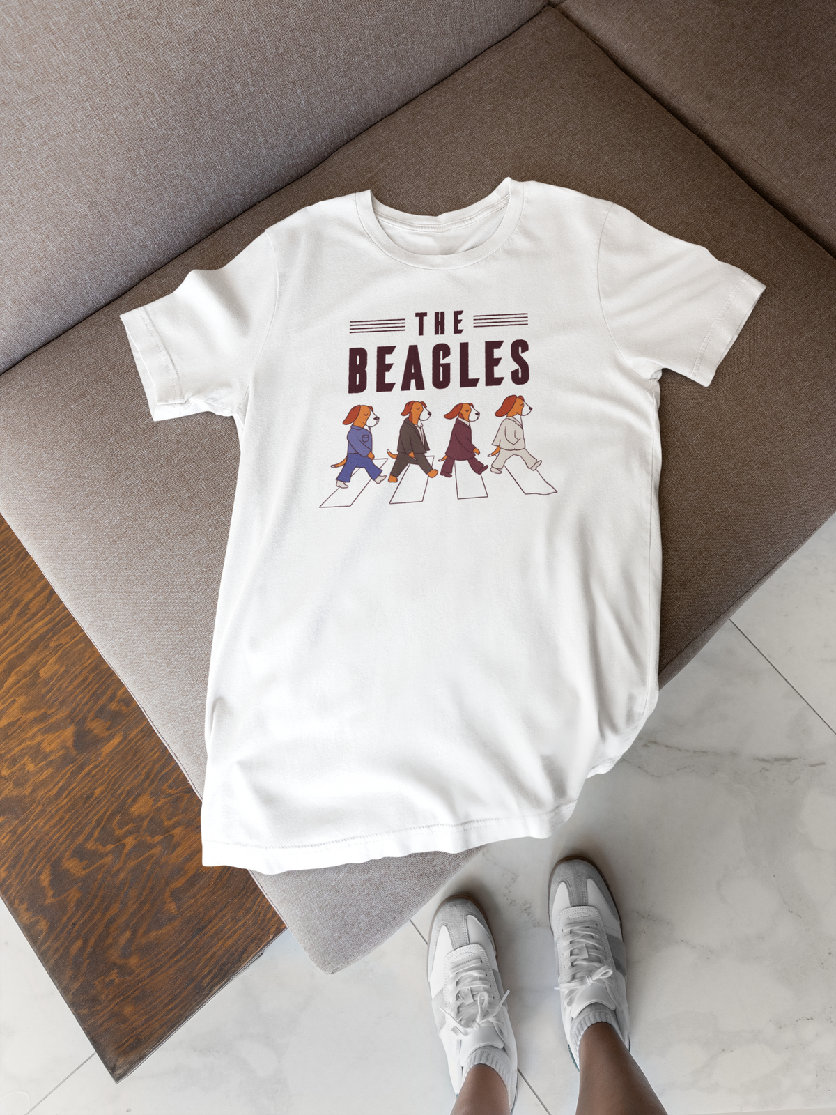 'The Beagles' t-shirt in white, flat lay on a bed with sneakers