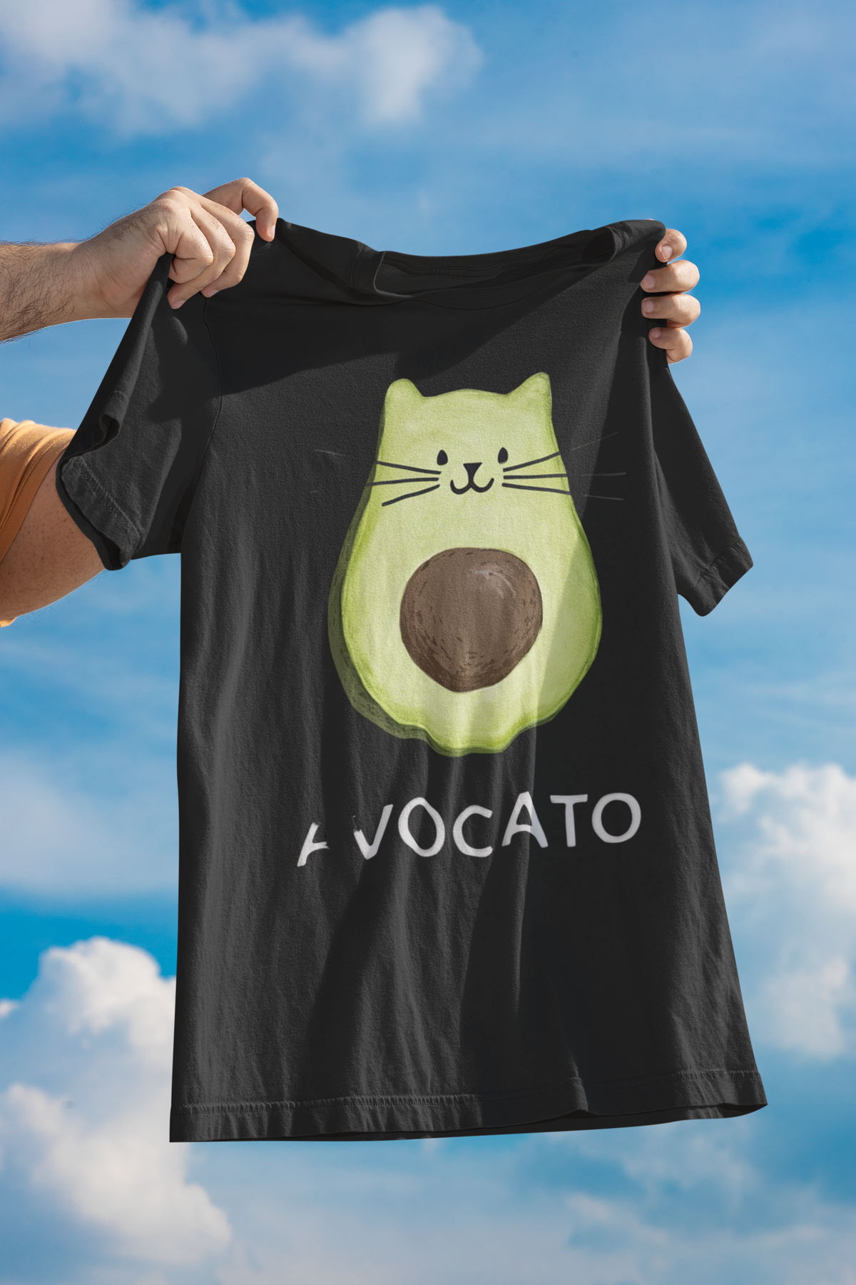'Avocato' cat avocado t-shirt in black, man holding it up outdoors under sky, funny cat gift