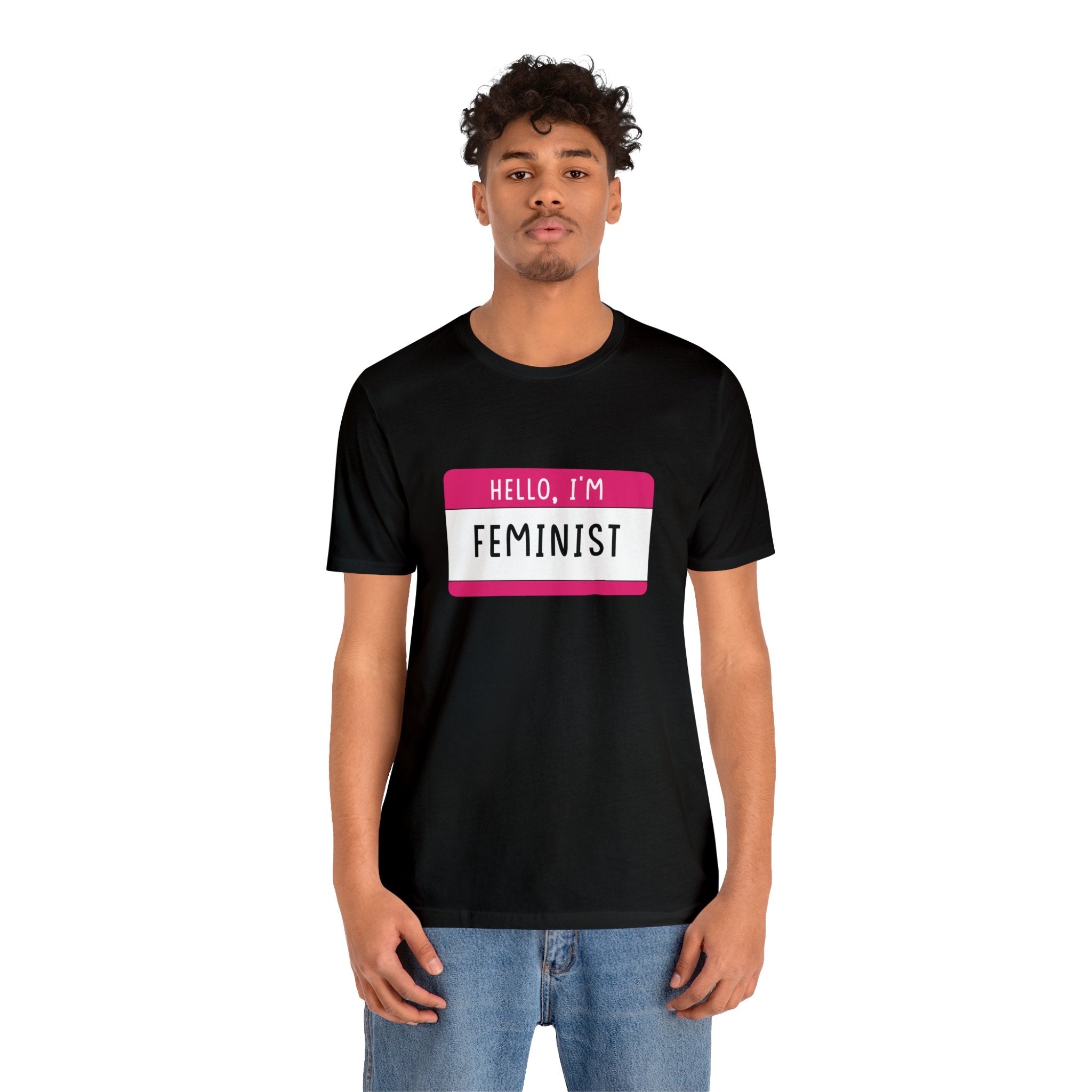 A young man wearing a Hello, I'm Feminist T-Shirt, standing against a white background.